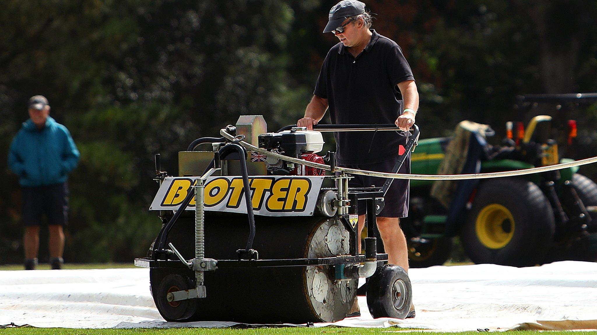 A groundsman uses a blotter machine in the hope of getting some play in the Hampshire-Essex game at Arundel