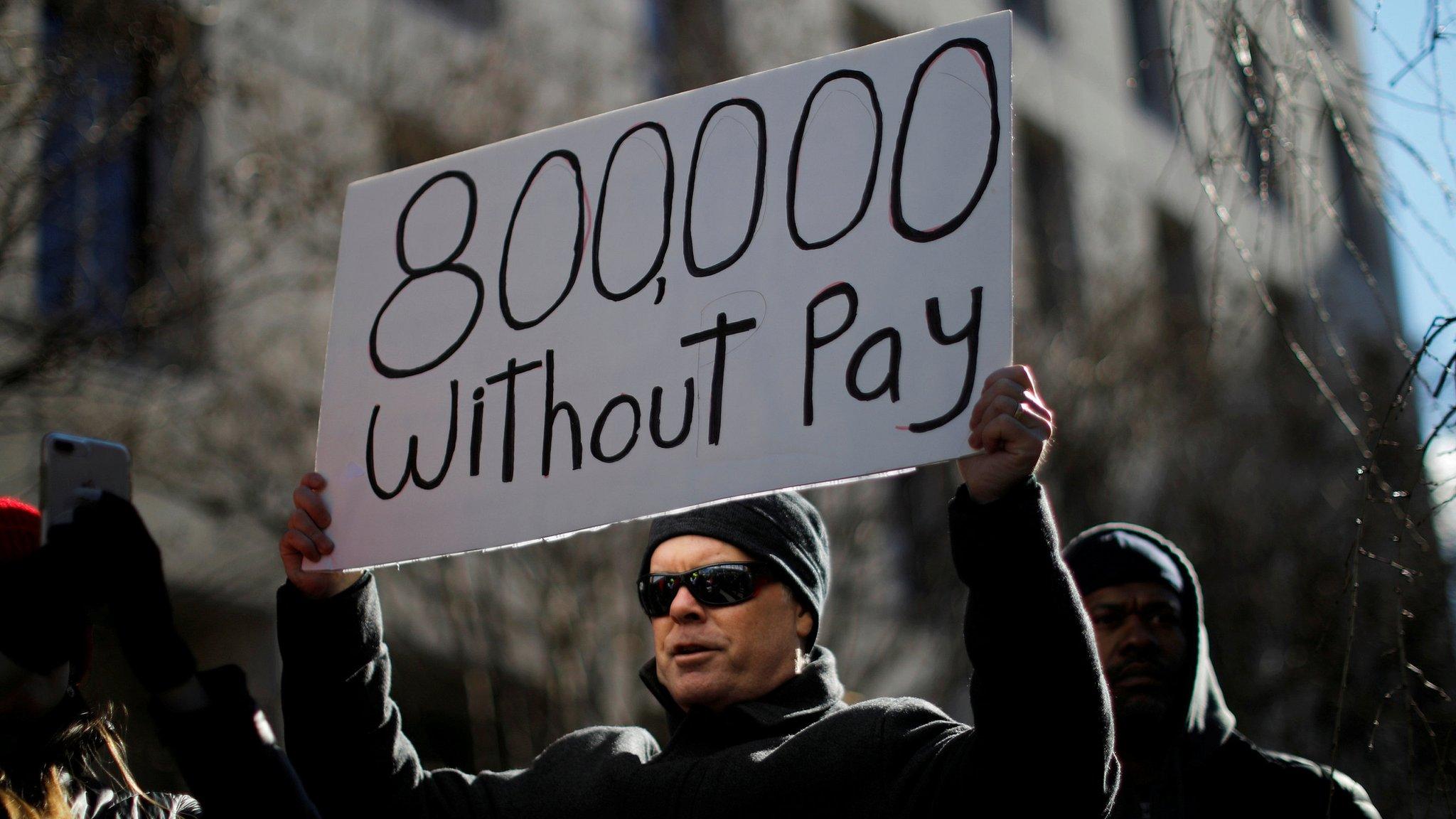 A protester holds a sign signifying hundreds of thousands of federal employees who won't receive salaries as a result of the partial government shutdown. Washington Jan 10 2019