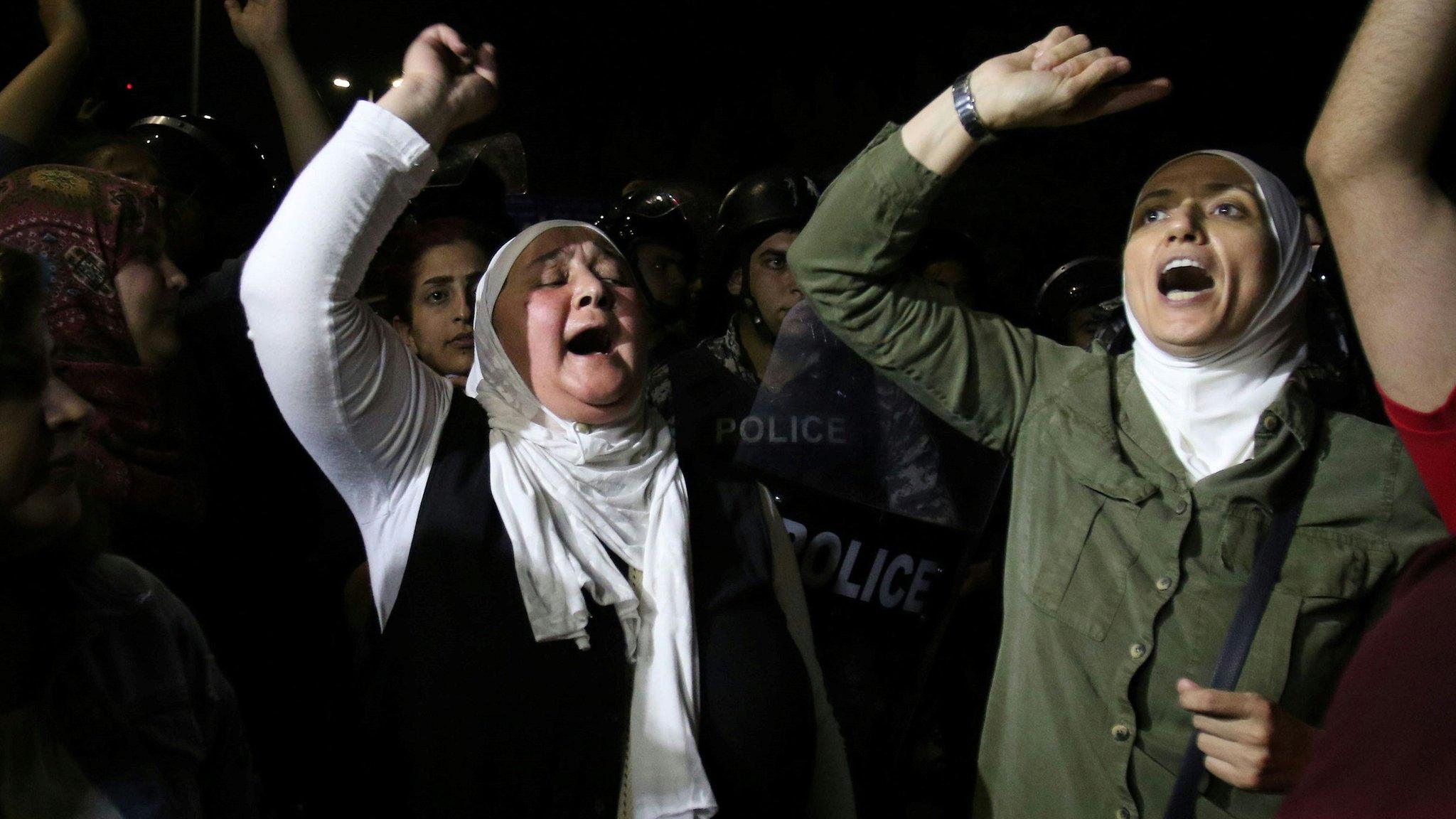 Protesters raise their fists near riot police officers during a demonstration outside the prime minister's office in the capital Amman late on June 3, 2018