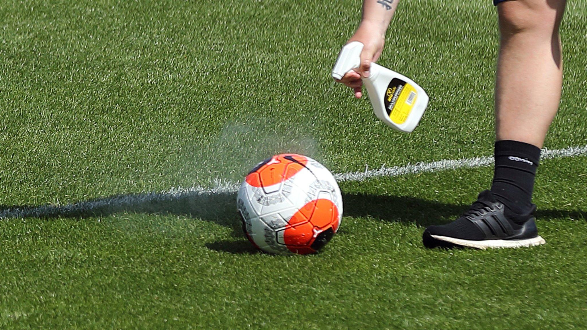 A member of staff sprays a ball with disinfectant