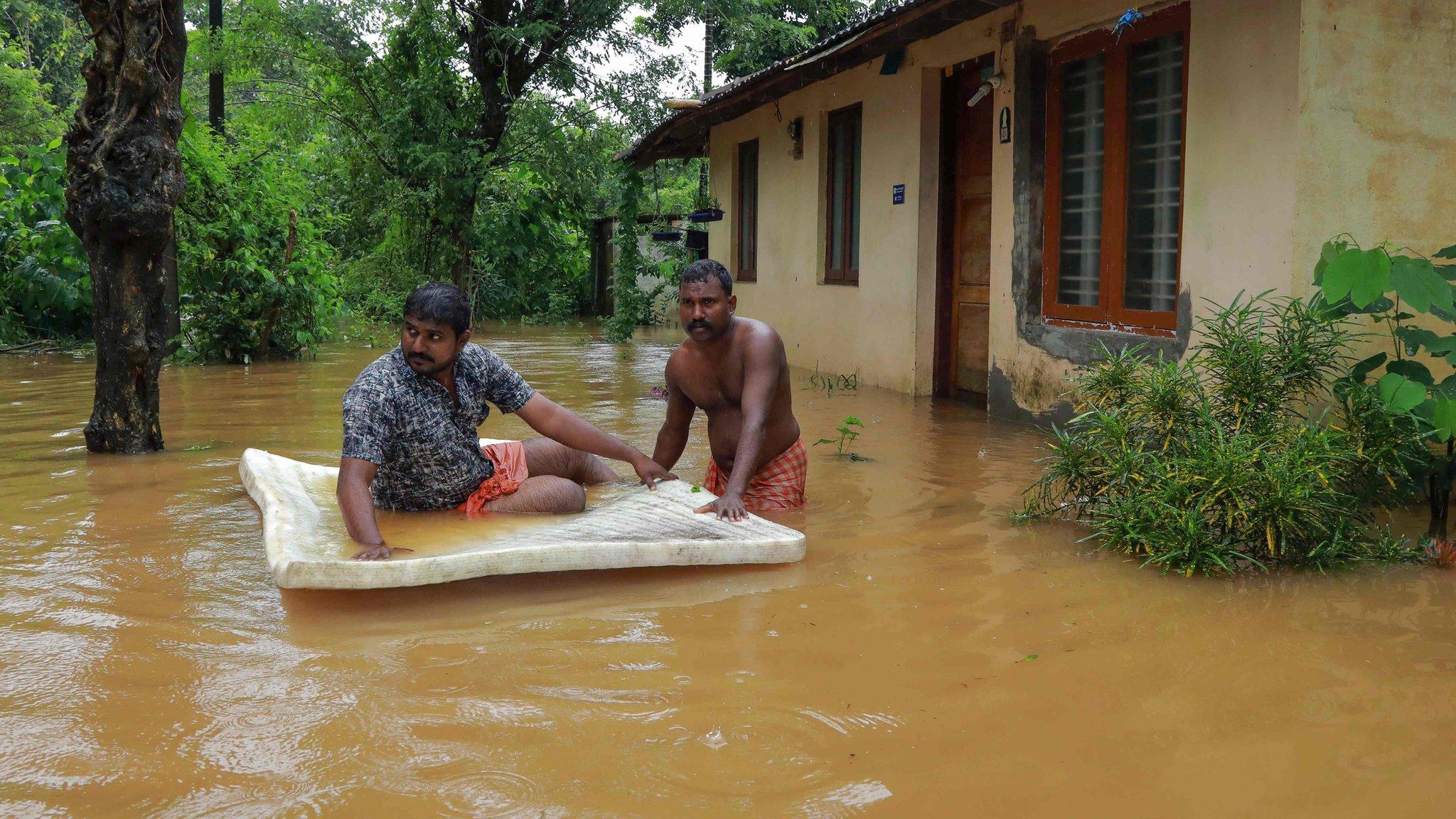 Men pass through flood waters in the southern Indian state of Kerala