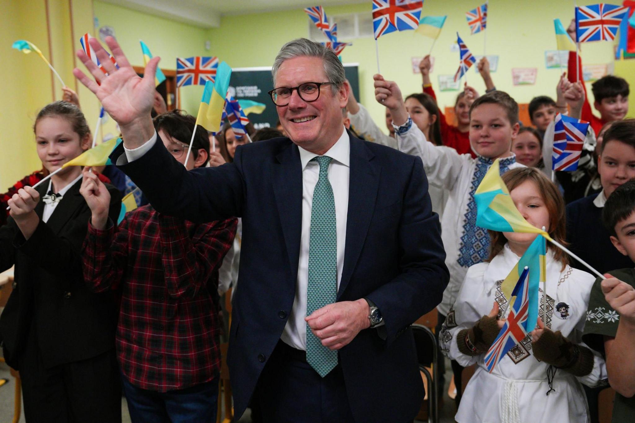 Prime Minister Keir Starmer waves with schoolchildren waving British and Ukraine flags in Kyiv 