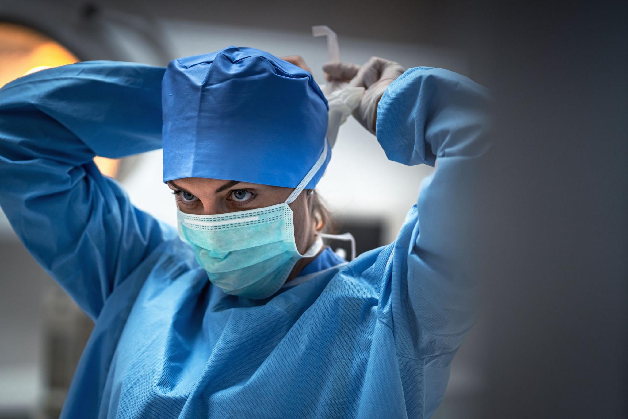 The surgeon is wearing a mask to prevent infection before surgery.