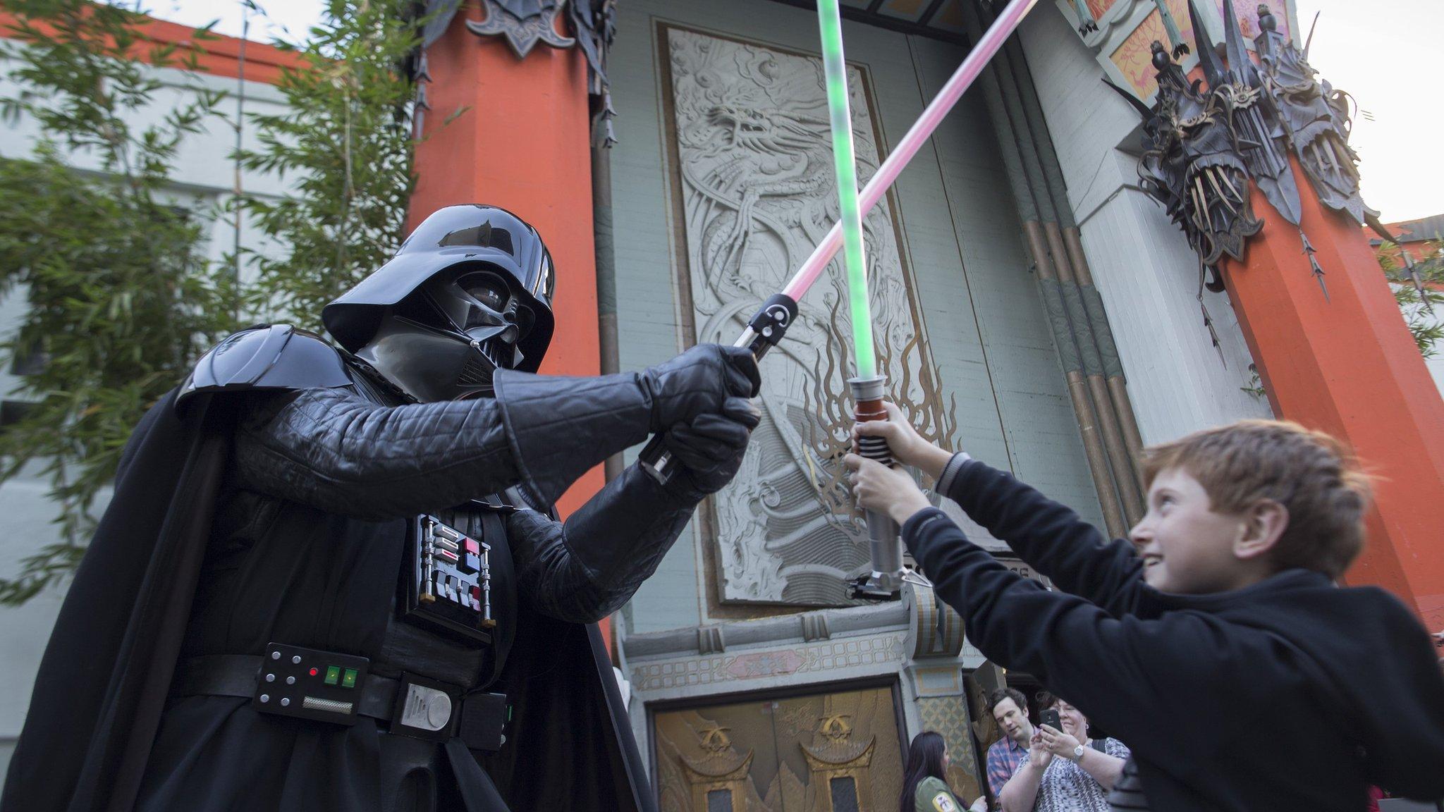 A boy battles Darth Vader with lightsabers