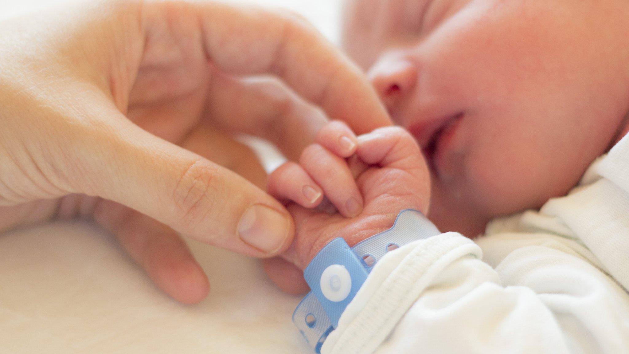 Parent holds the hand of a baby