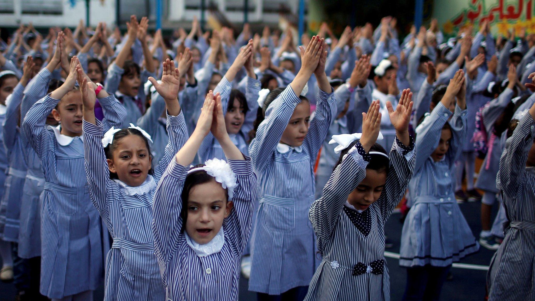 Palestinian school girls raise their hands during a morning exercise at a Unrwa-run school, in Gaza City, on 29 August 2018