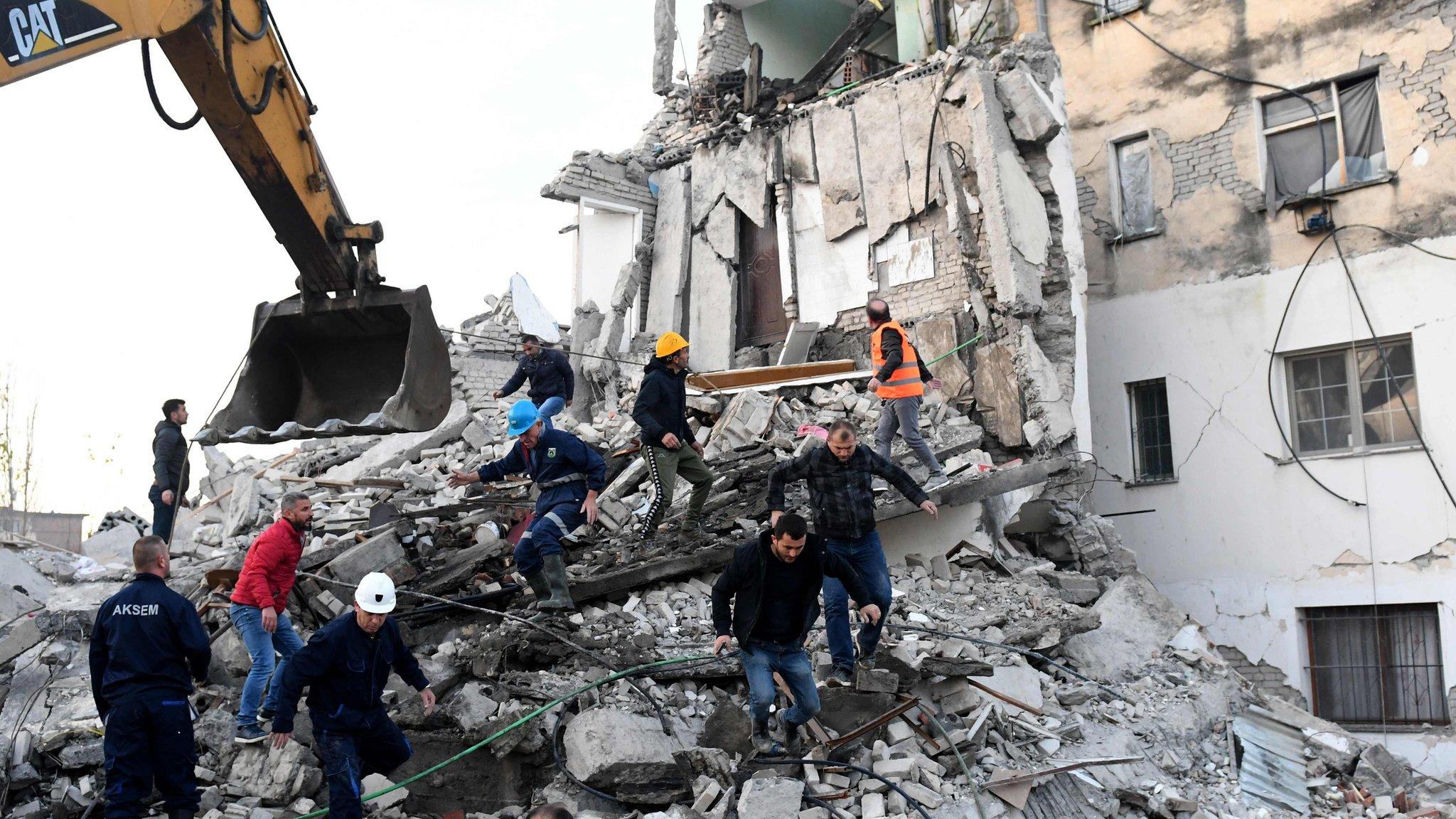 Emergency workers clear debris at a damaged building in Thumane