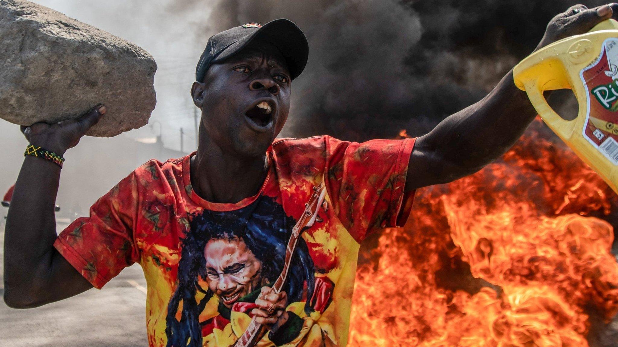 A protester reacts in front of burning tires during the protest against the government and high cost of living called by Kenya's opposition leader Raila Odinga