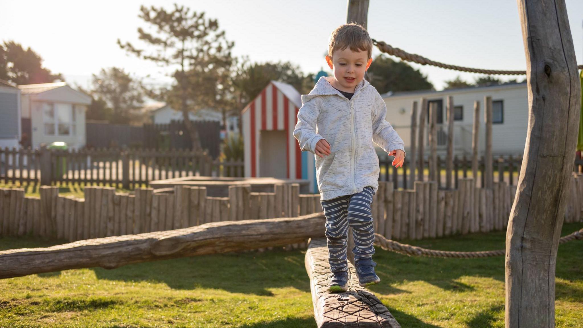 A young boy runs along a wooden balance beam