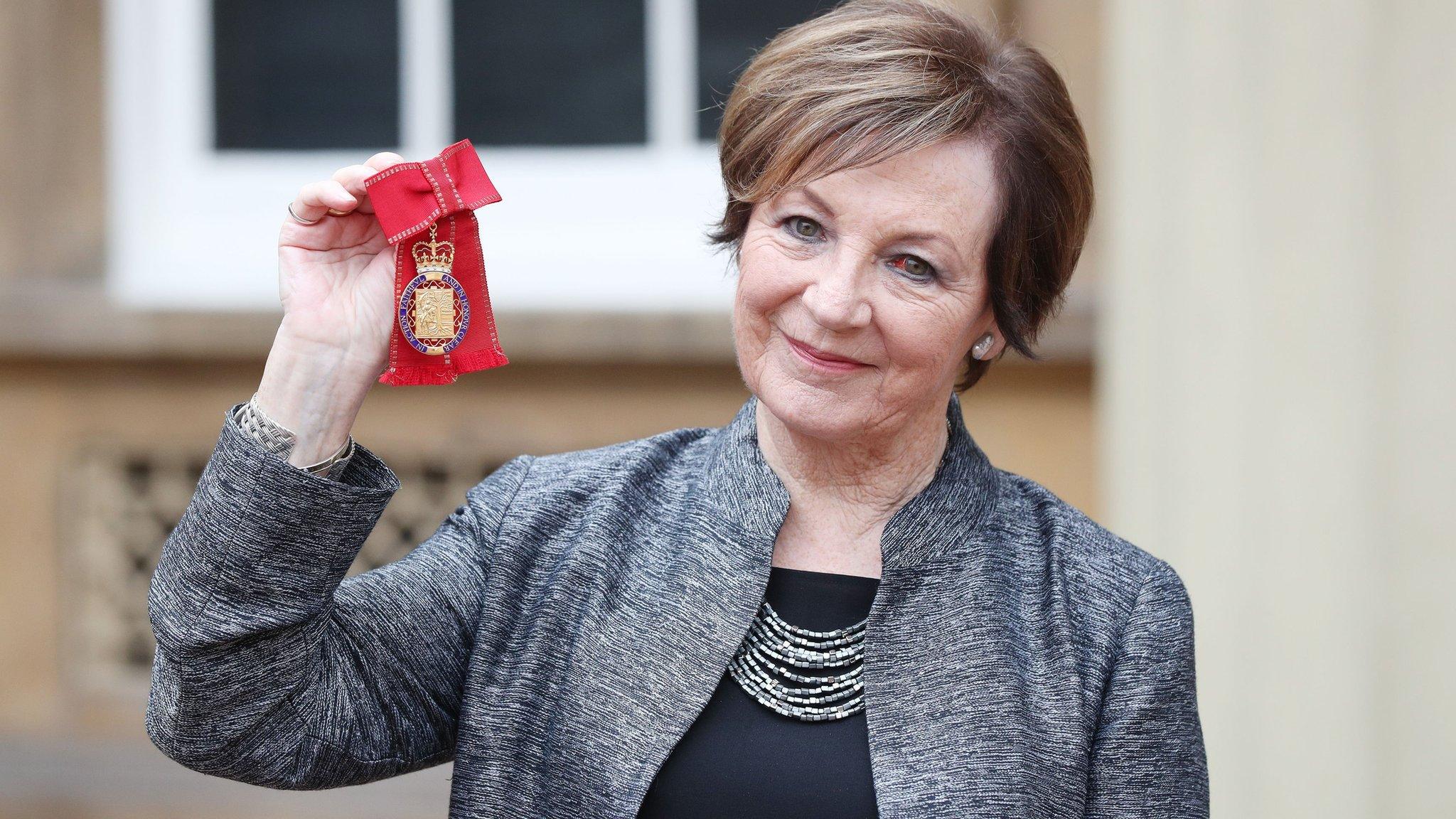 Delia Smith holding up her honour at Buckingham Palace