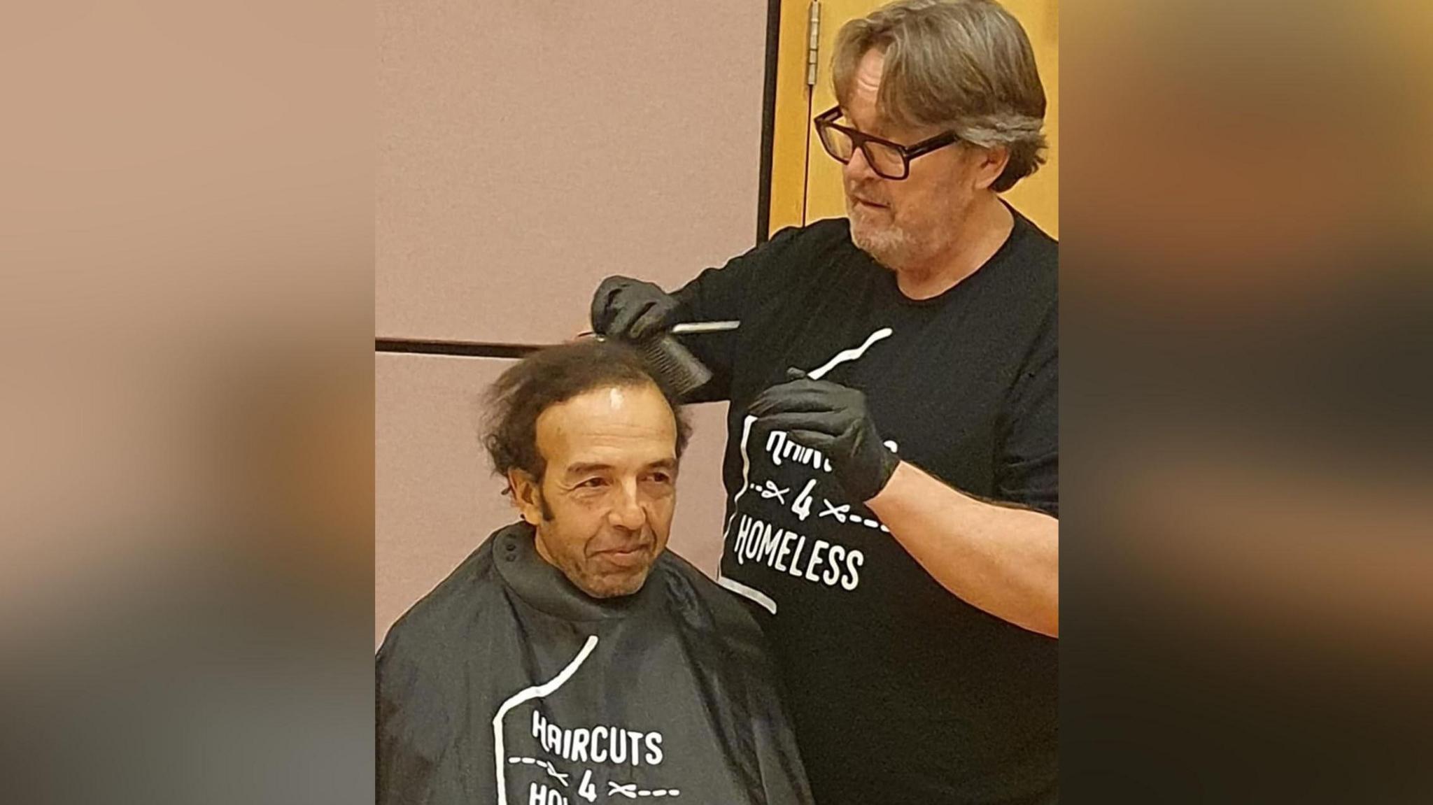 Llun Stewart yn torri gwallt dyn arall.