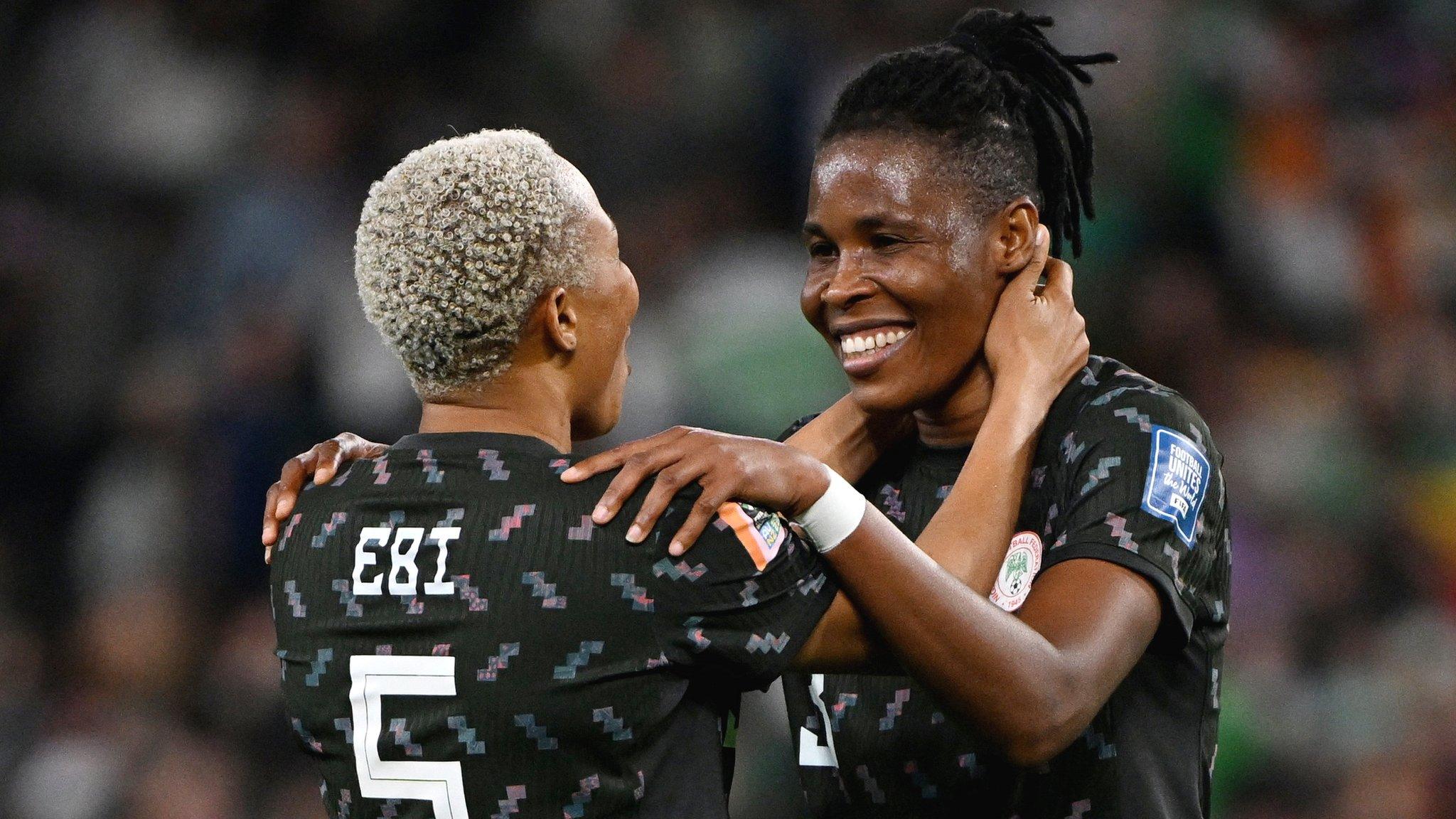 Nigerian duo Onome Ebi and Osinachi Ohale look at each other and smile while placing hands around each others shoulders