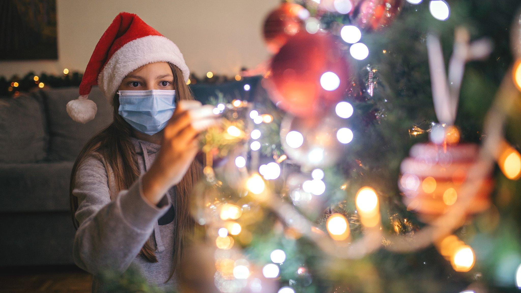 girl-decorating-christmas-tree-wearing-masks