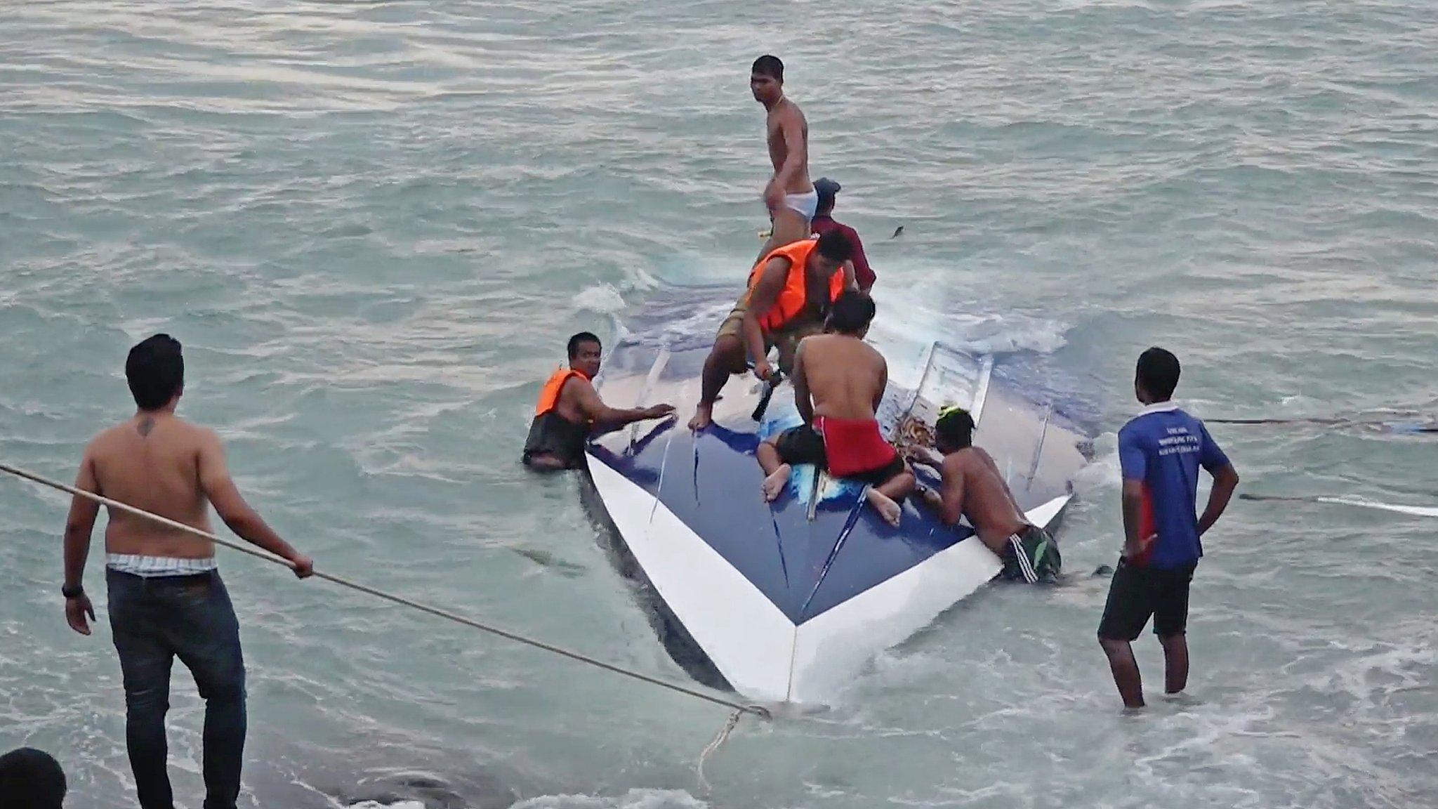 Rescuers on top of the capsized boat