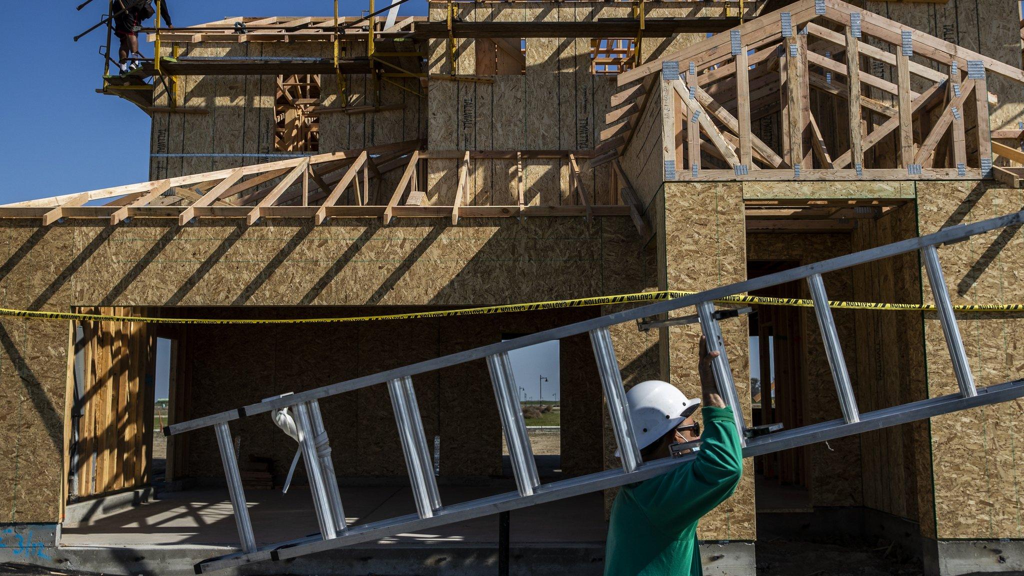 A worker carries a ladder into a home under construction at the planned community at River Islands in Lathrop, California Thursday, Mar. 4, 2021.