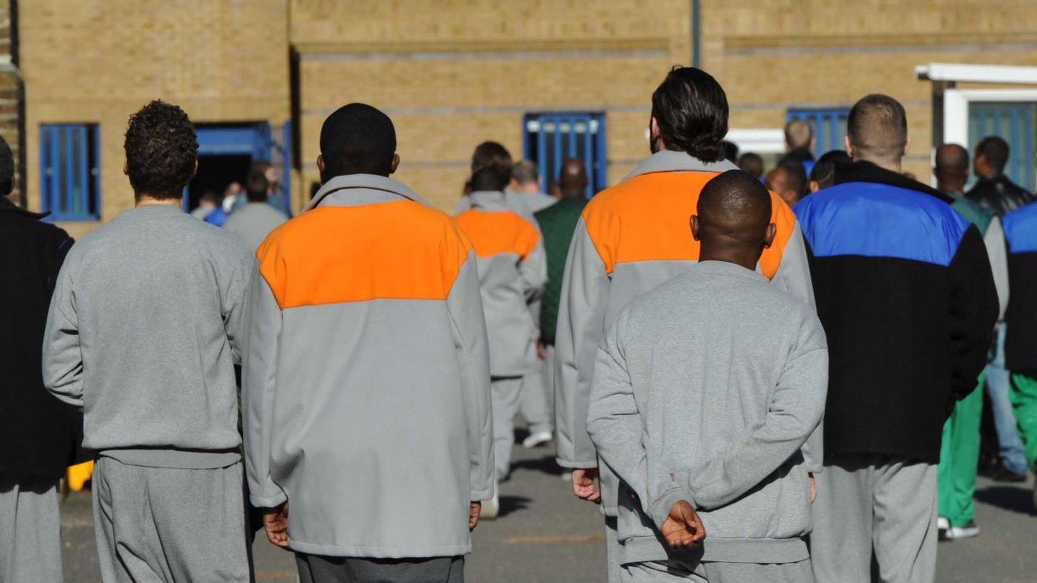 Male prisoners seen from behind in the exercise yard of Wormwood Scrubs, a prison in London