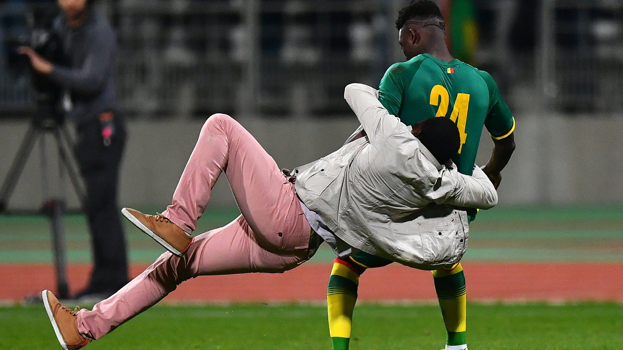 An Ivory Coast players is rugby tackled by a fan