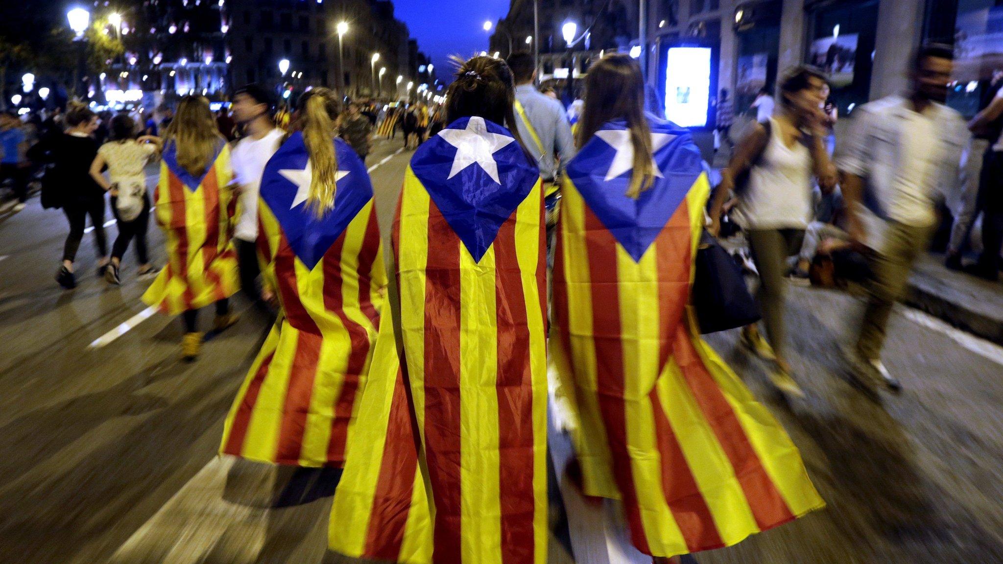 Catalan people wearing pro-independence "Estelada" flags leave after a protest at Barcelona University, 3 October 2017