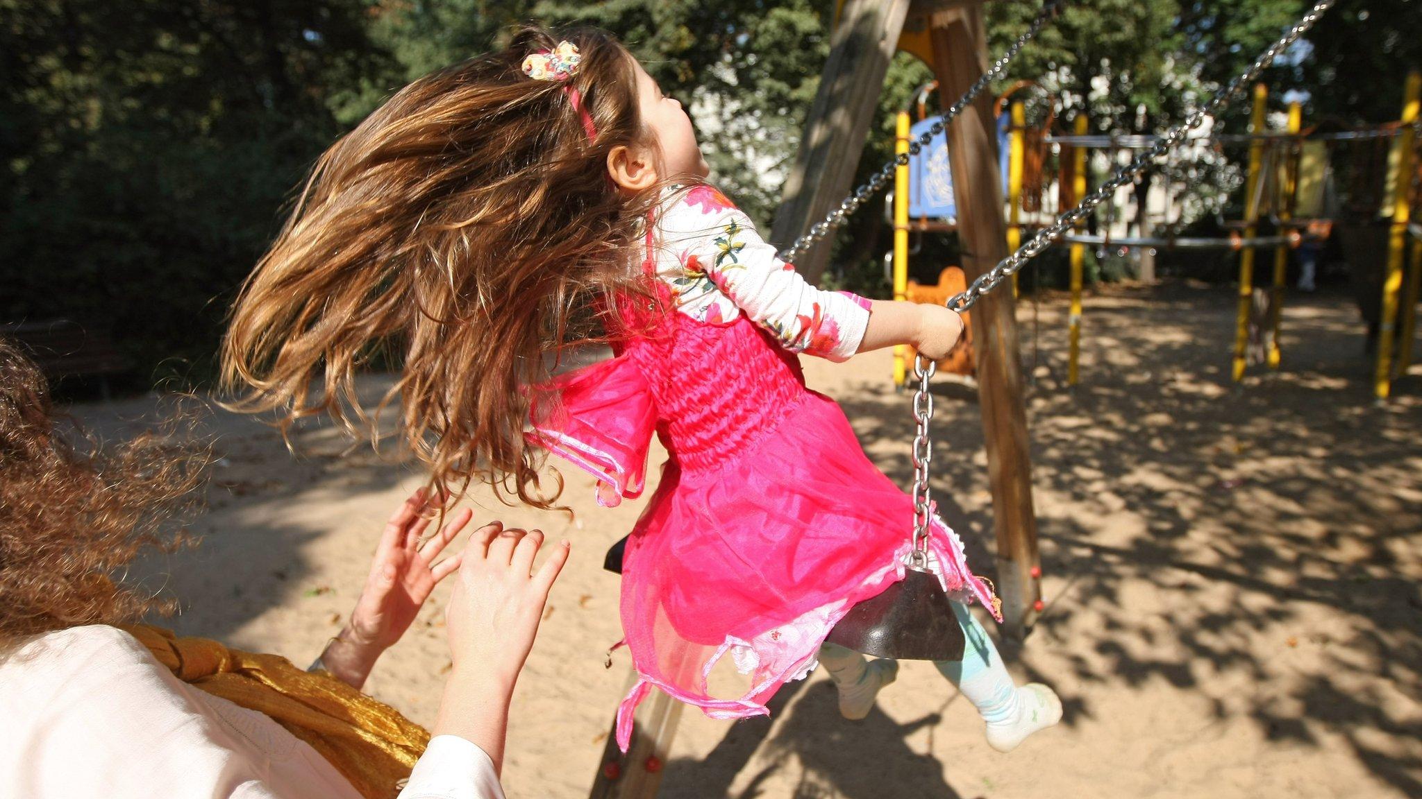 An anonymous mother pushes her three-year-old daughter on a swing in Berlin, 2012