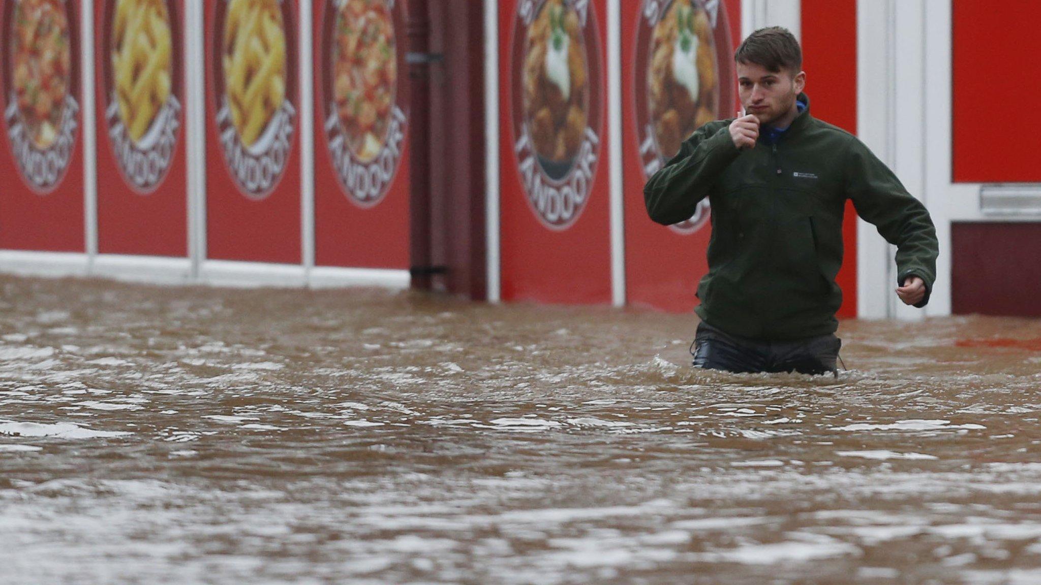 Man wades through flood water in Dumfries