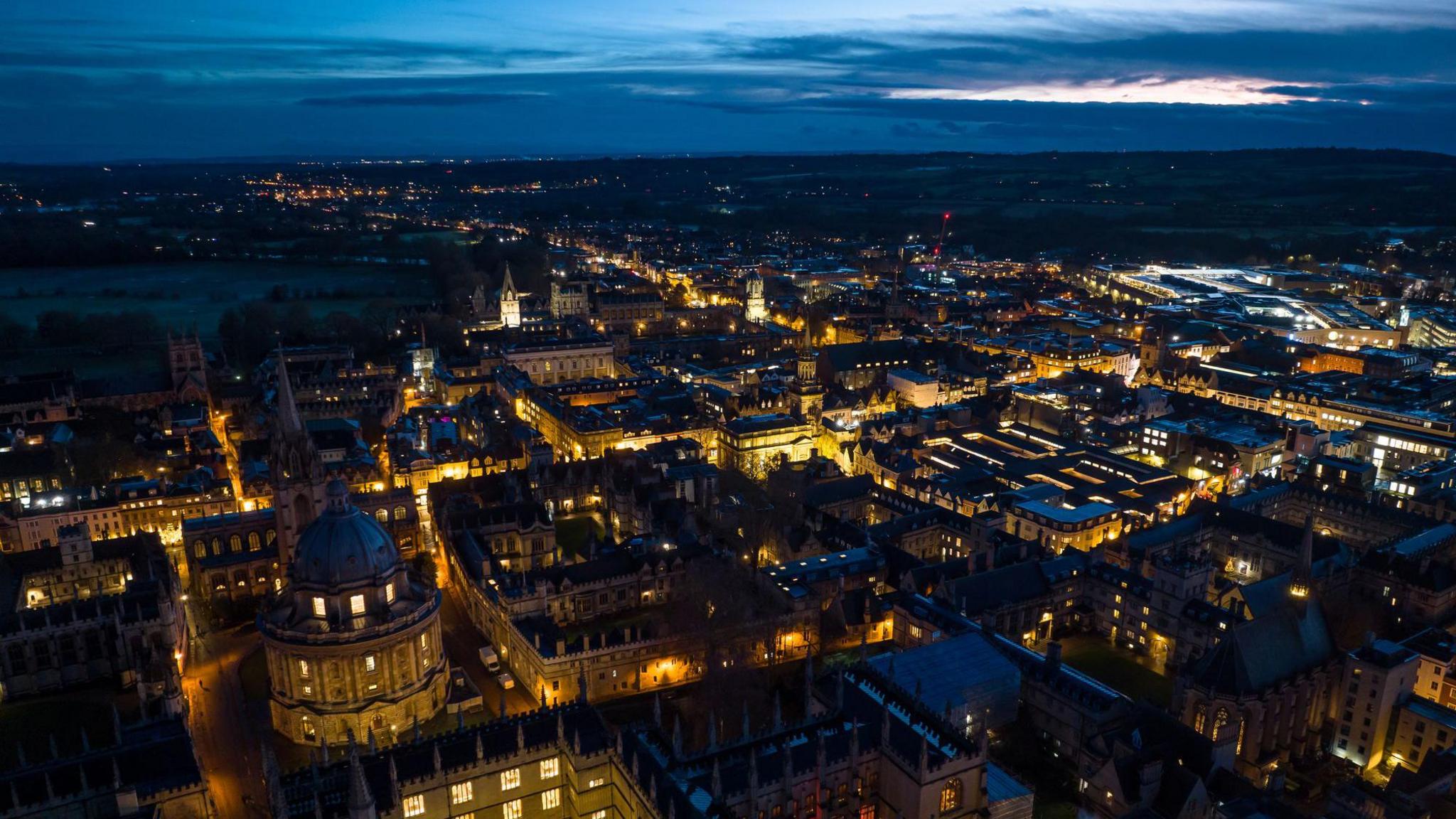 A bird's eye view of Oxford at night, with the Radcliffe Camera and the historic centre of the city illuminated by electric lights 