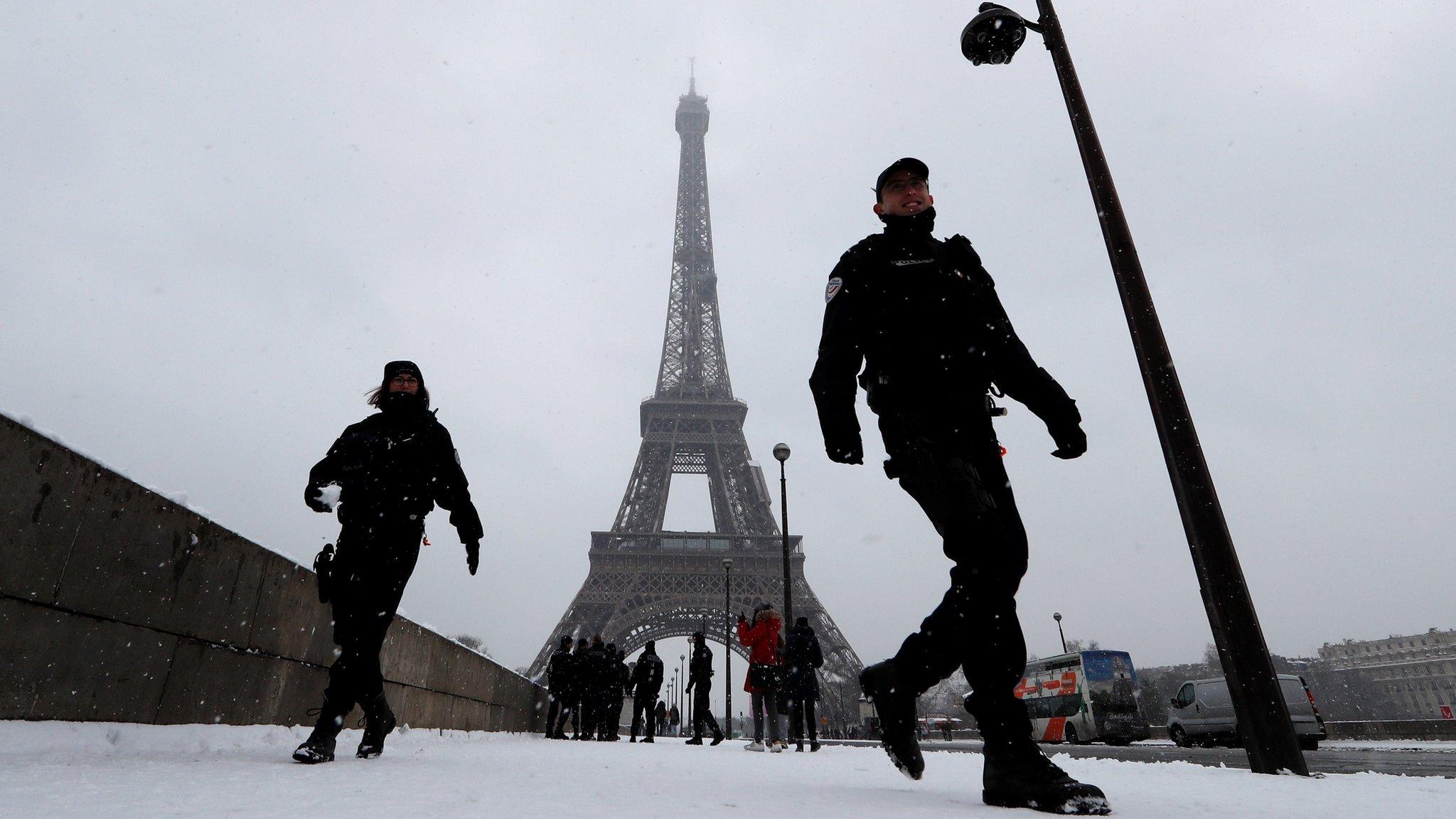 French police patrol near the Eiffel Tower in Paris under the falling snow as winter weather continues in northern France, February 9, 2018