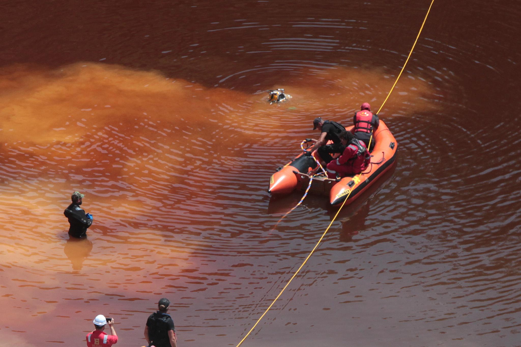 Forensic officers, rescuers and divers retrieve a suitcase, which police say contains a female body