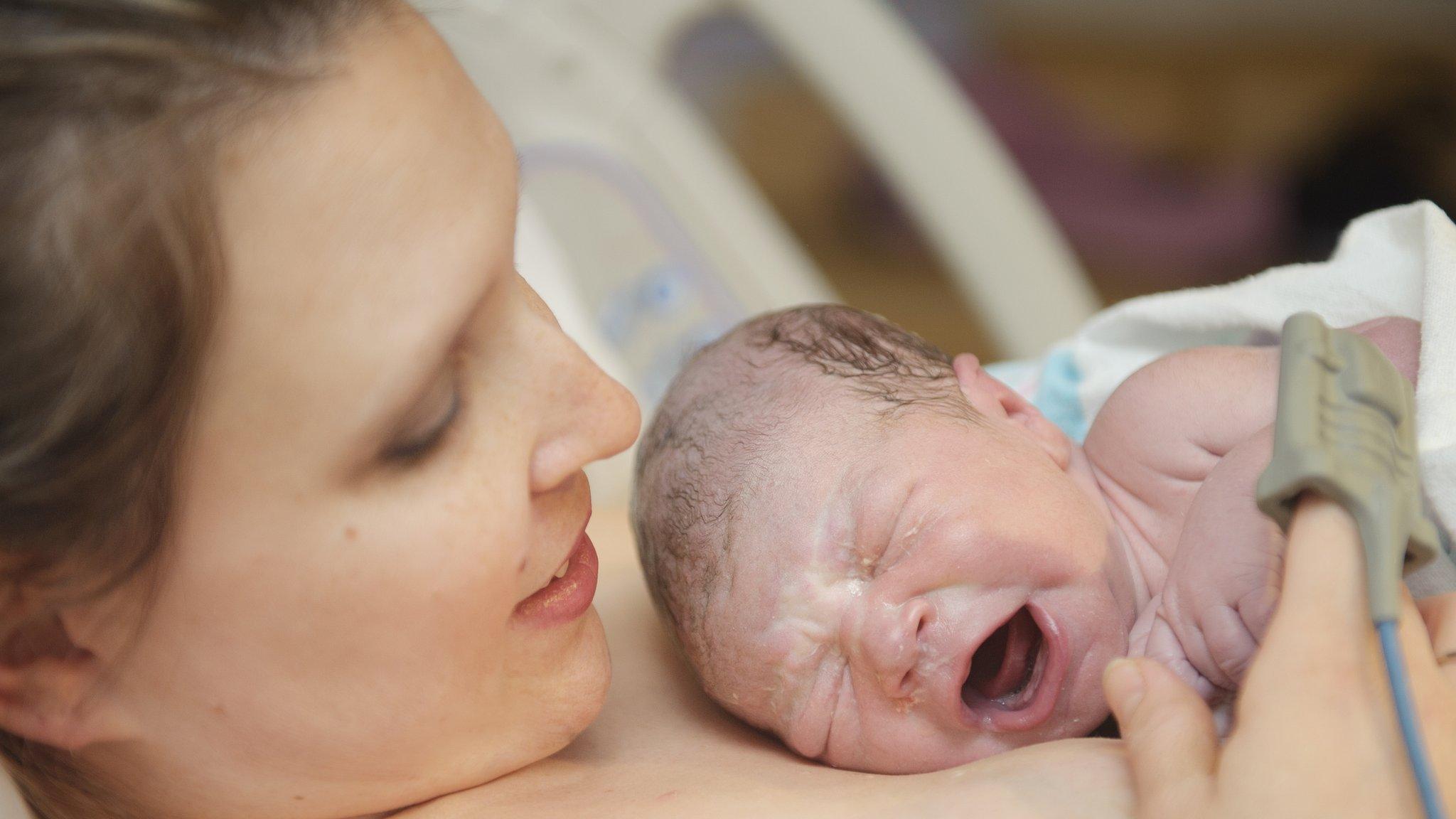 woman in hospital with new born baby on her chest