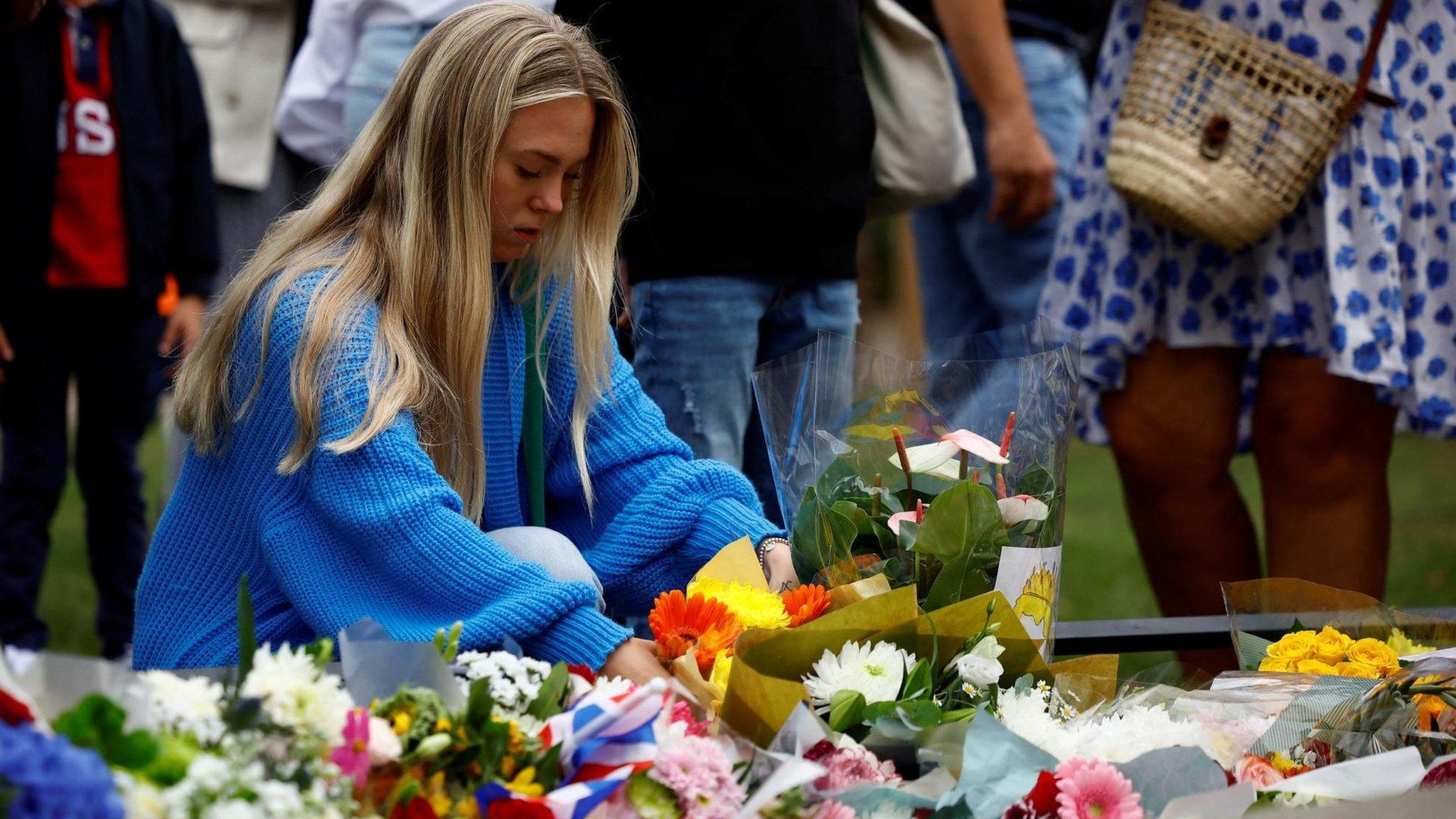 A woman places flowers in St. James' Park near Buckingham Palace (10 September 2022)