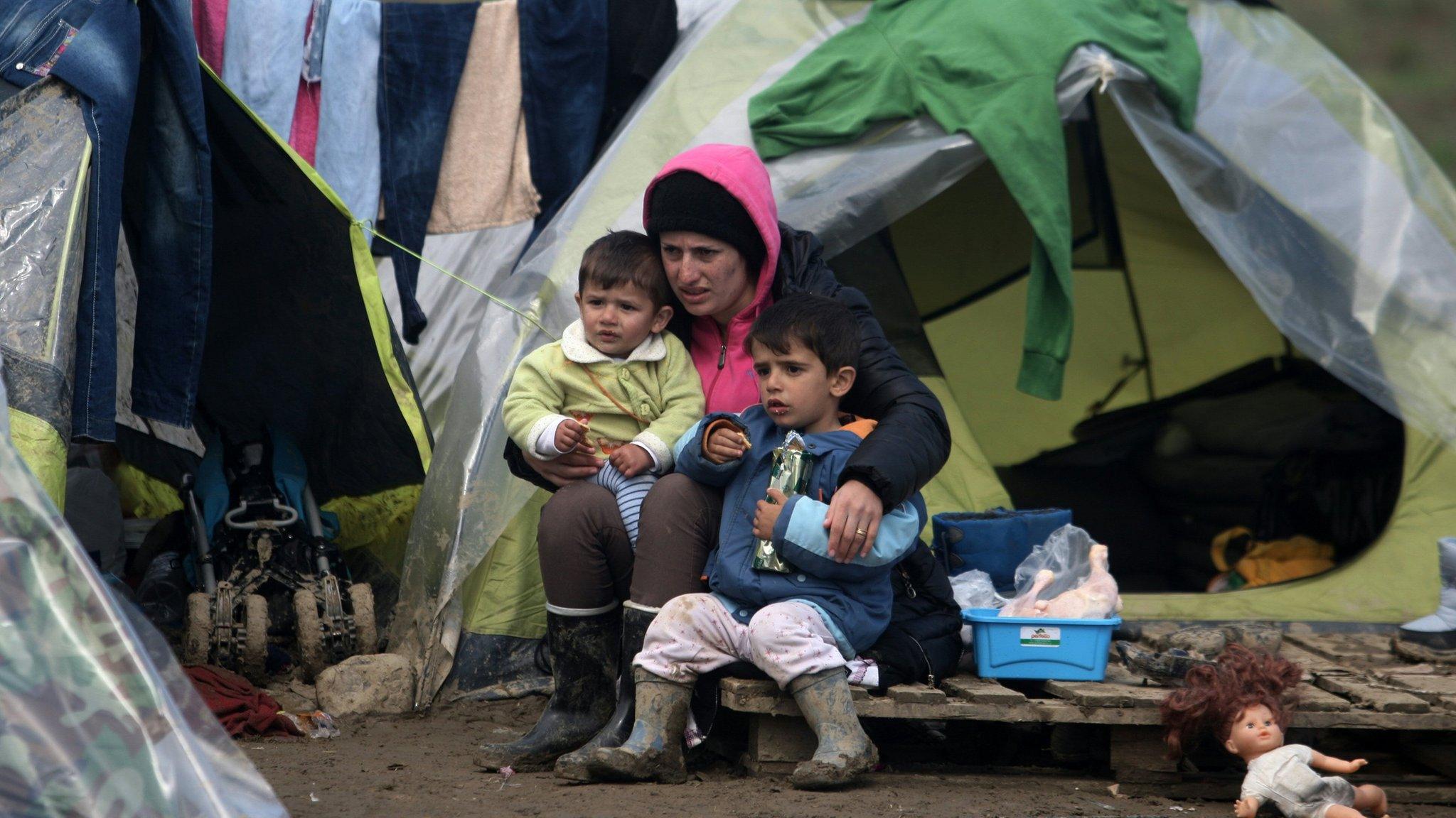 A woman and her children sit at a makeshift camp set by migrants and refugees at the Greek-Macedonian border, near the Greek village of Idomeni (March 17, 2016)