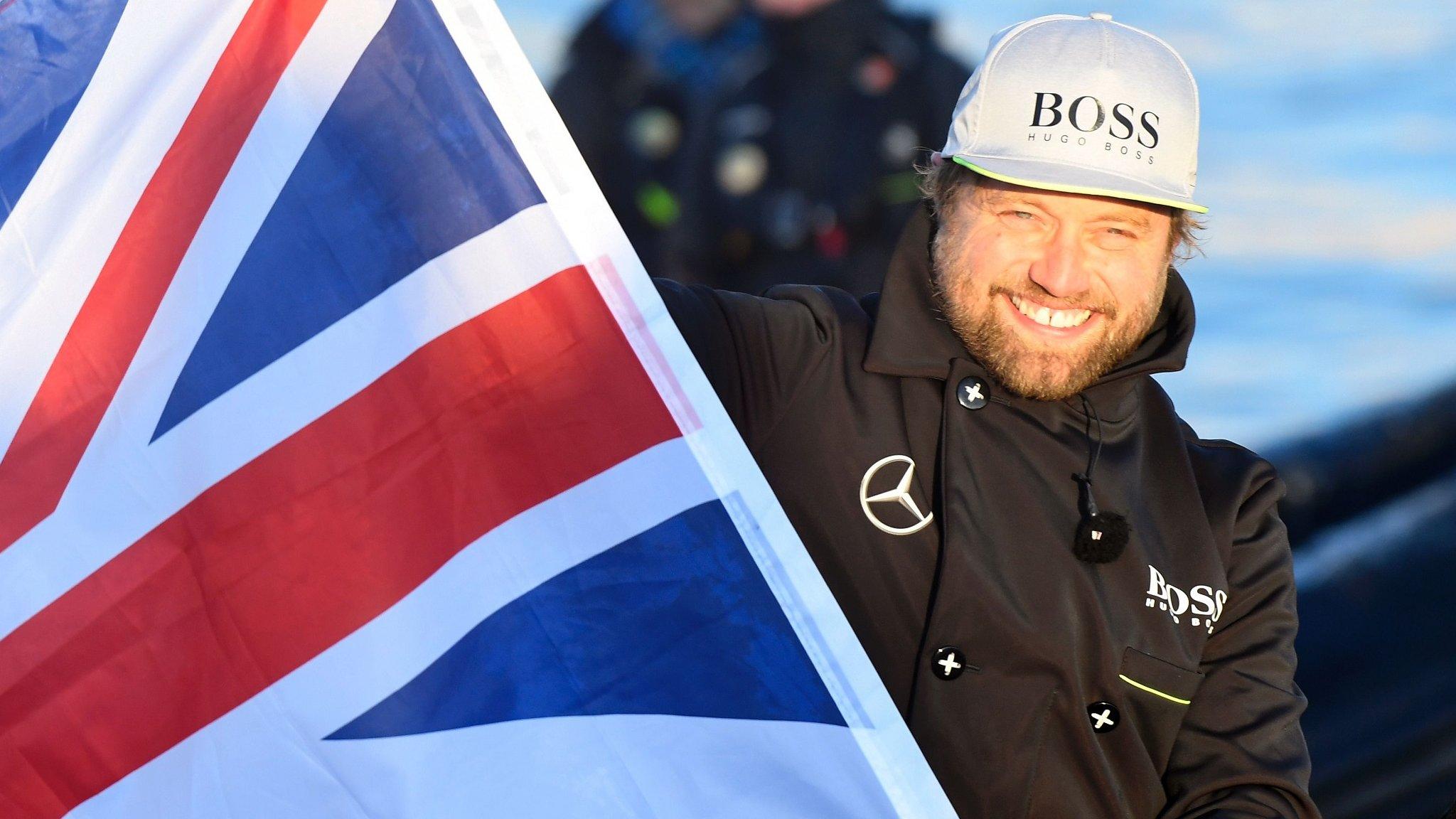 Alex Thomson waves the Union Flag after completing the Vendee Globe round the word yacht race