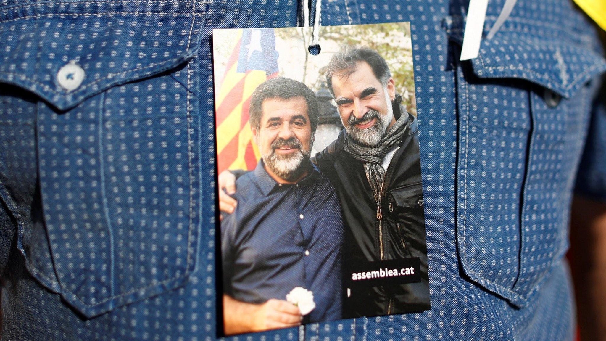 A supporter of Catalan independence holds a picture of two leaders of Catalan separatist groups, Jordi Sanchez and Jordi Cuixart