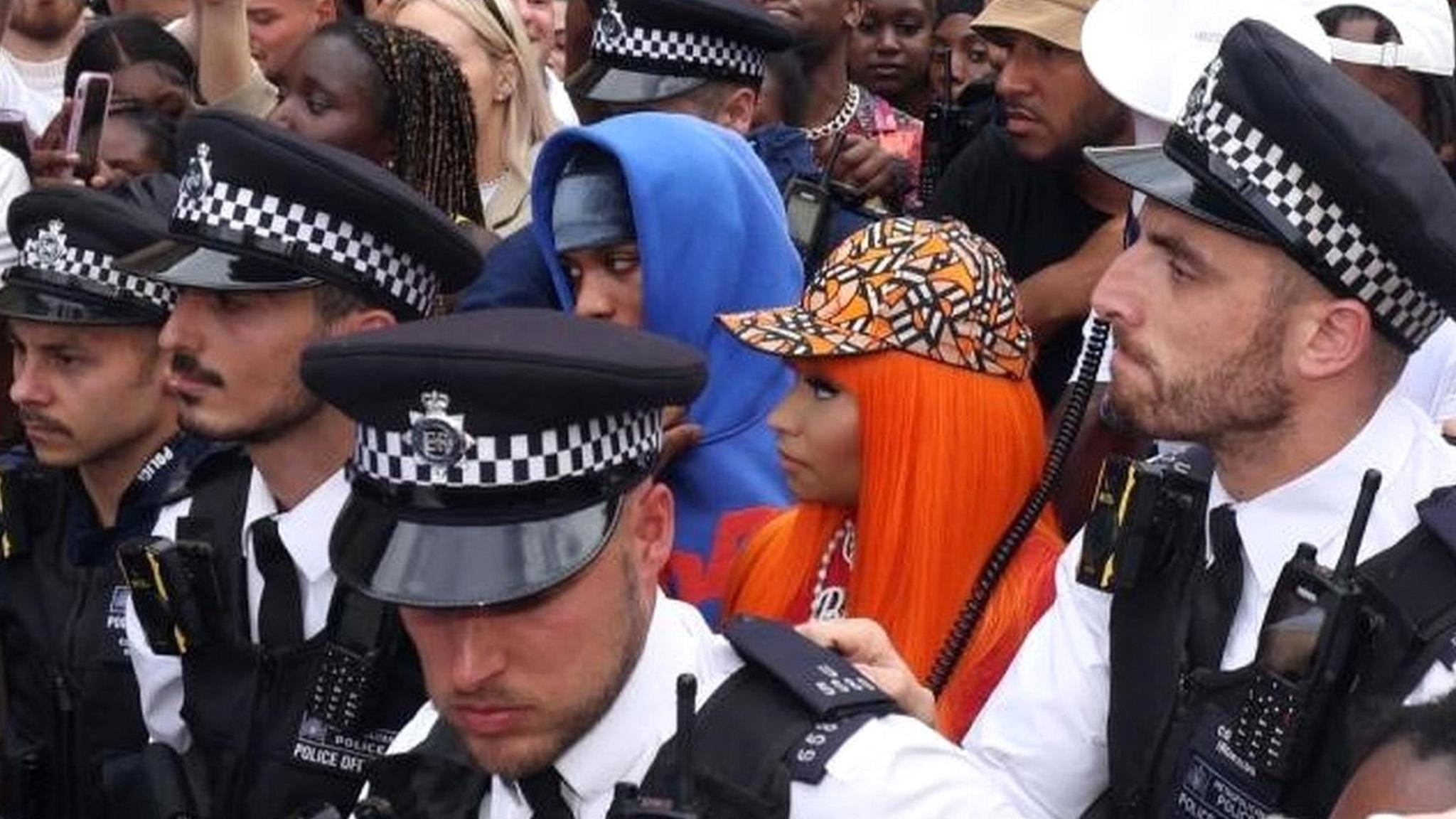 Police officers surround US rapper Nicki Minaj at fans attend a meet and greet at Camden's Cafe Koko