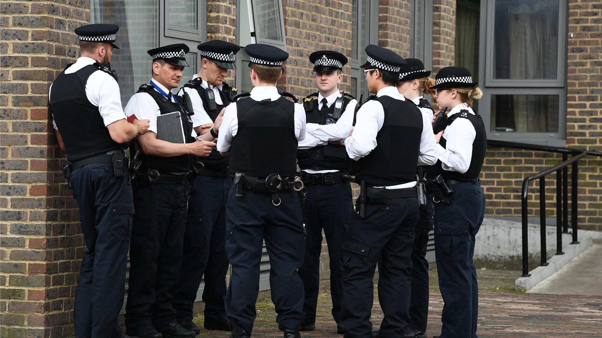 police in uniform stand in a huddle