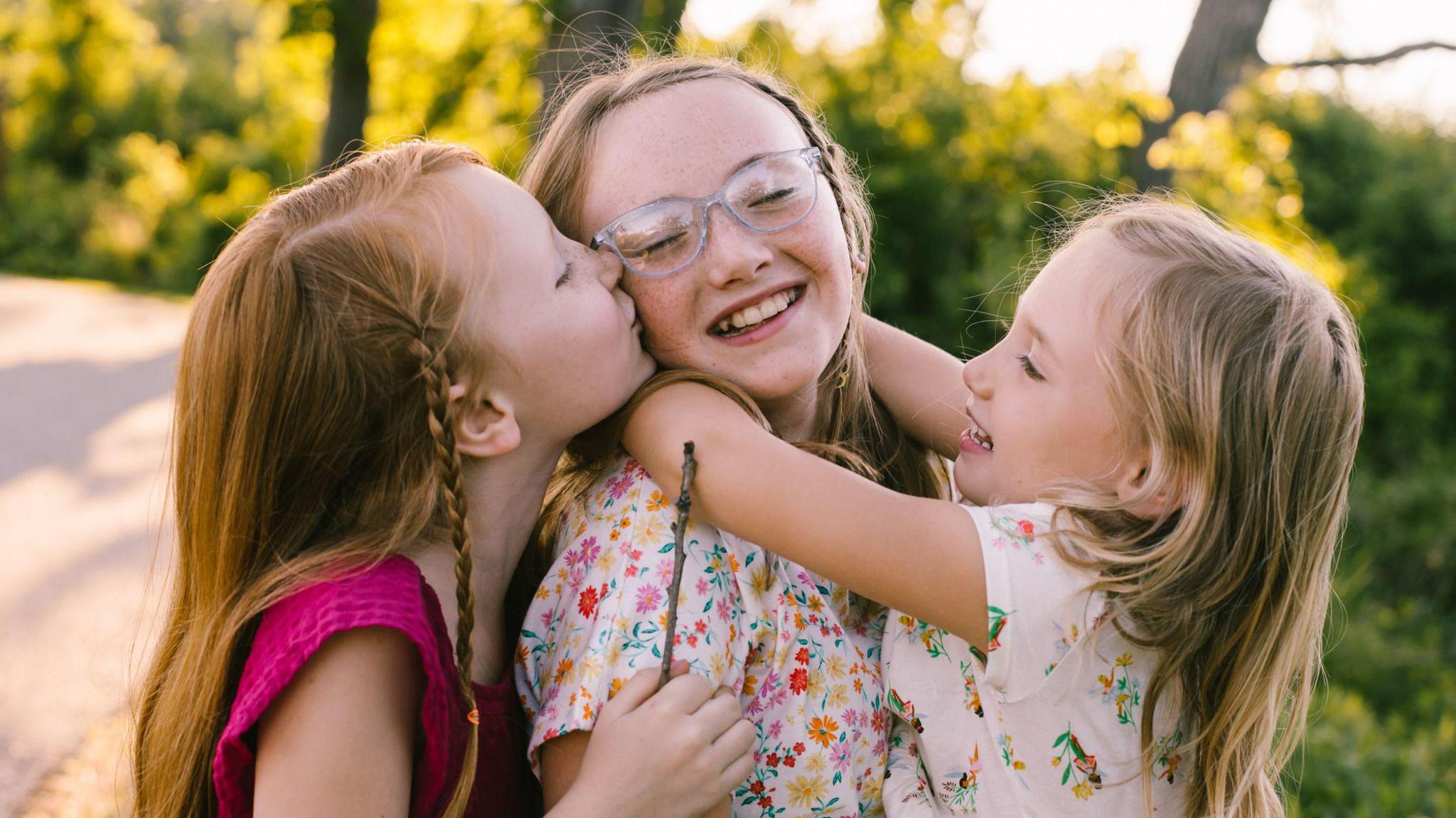 three girls hugging and kissing on cheeks