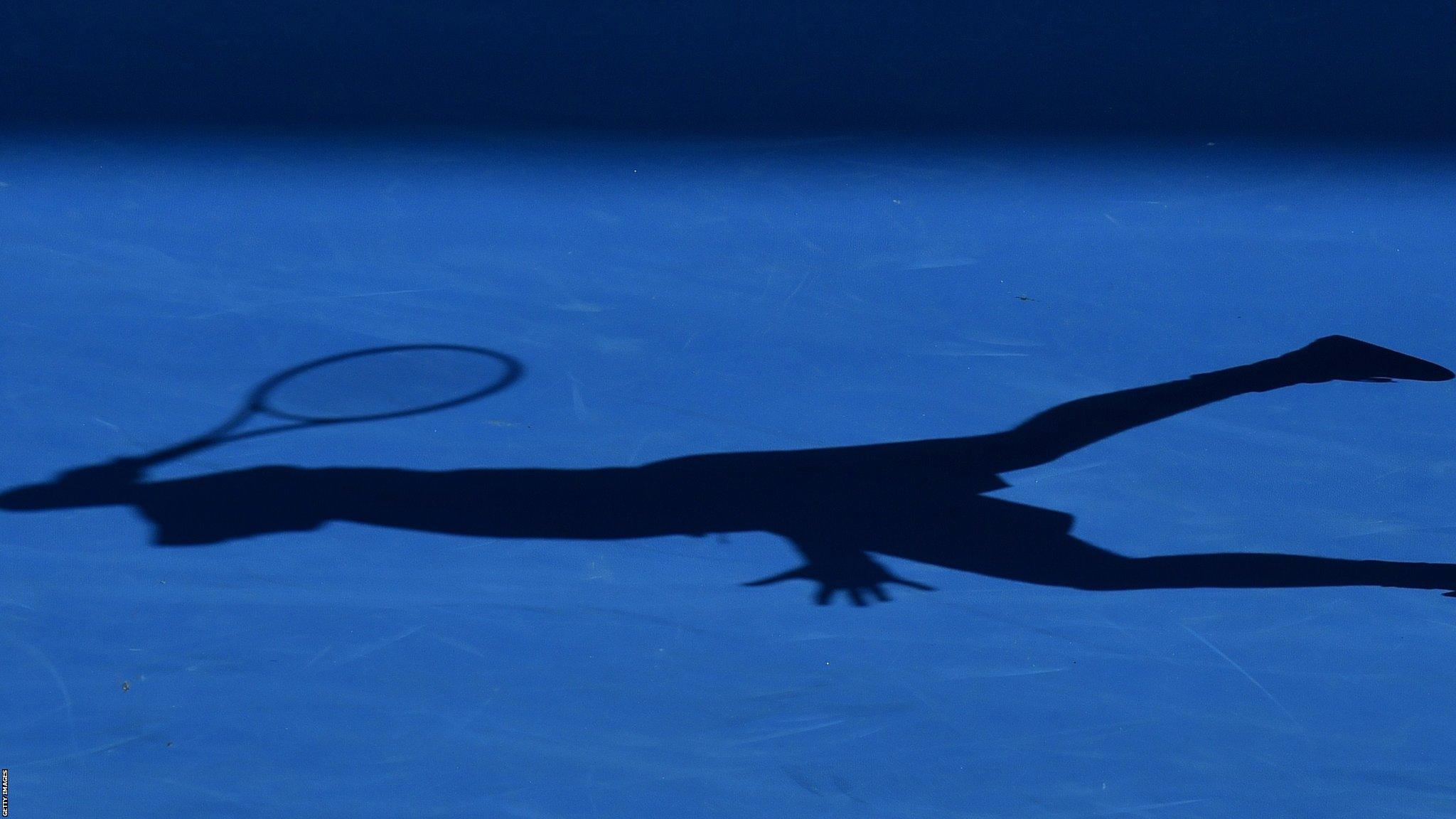 A tennis player casts a shadow