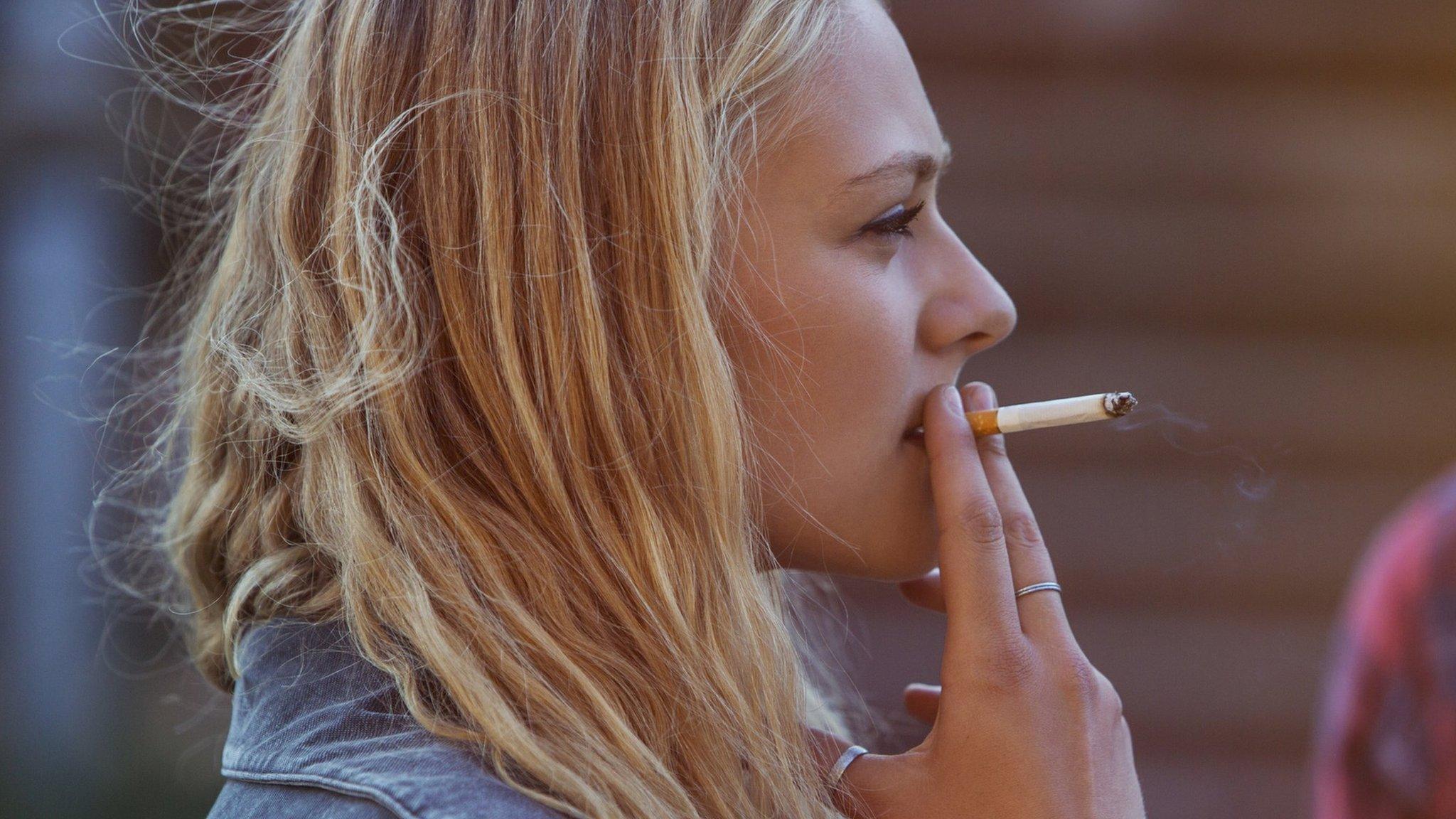 Blonde woman smoking cigarette - stock photo