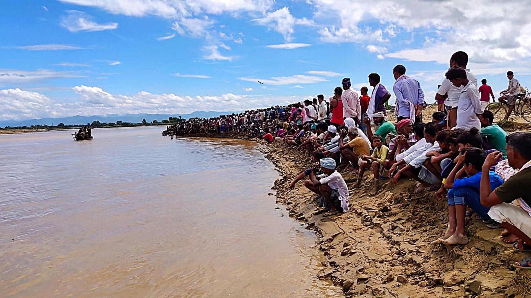 Villagers watch the searching operations of the missing persons after a Boat carrying 20 people drowned in the Bhada River at Lokahi villege of District Bahraich in Uttar Pradesh on Sunday. 