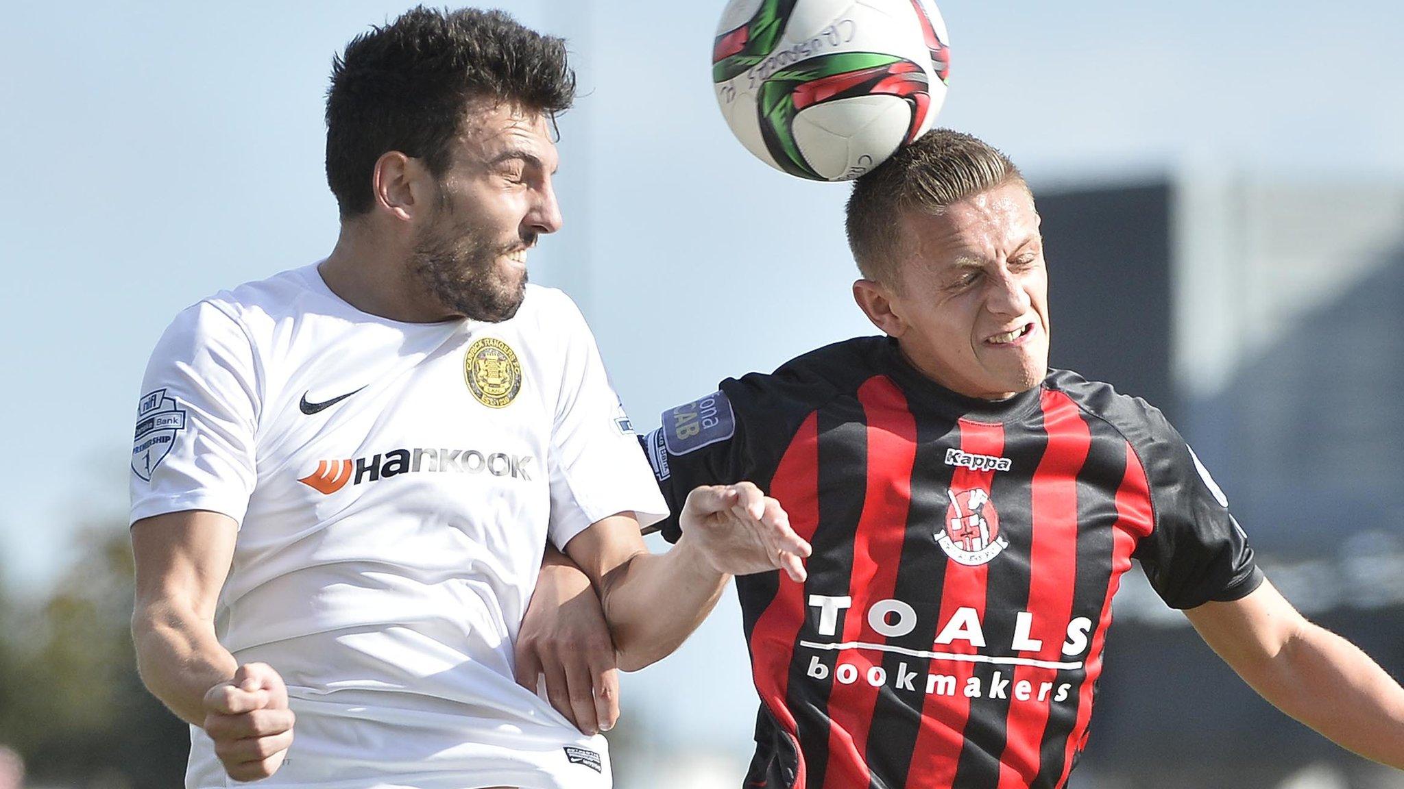 Carrick's Conor McCloskey and Crusaders midfielder Matthew contest a high ball