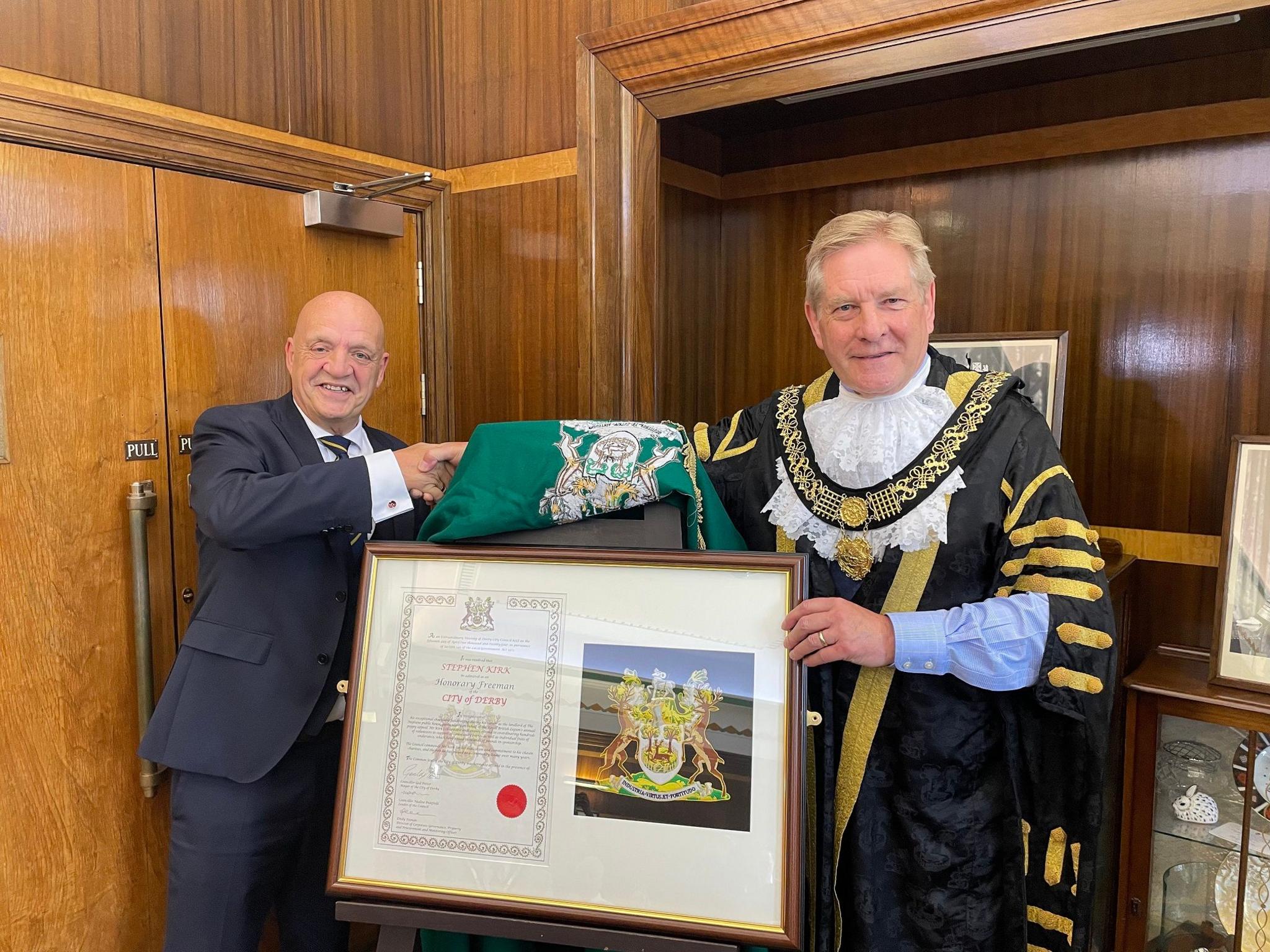 Mayor shaking hand of landlord with his civic award