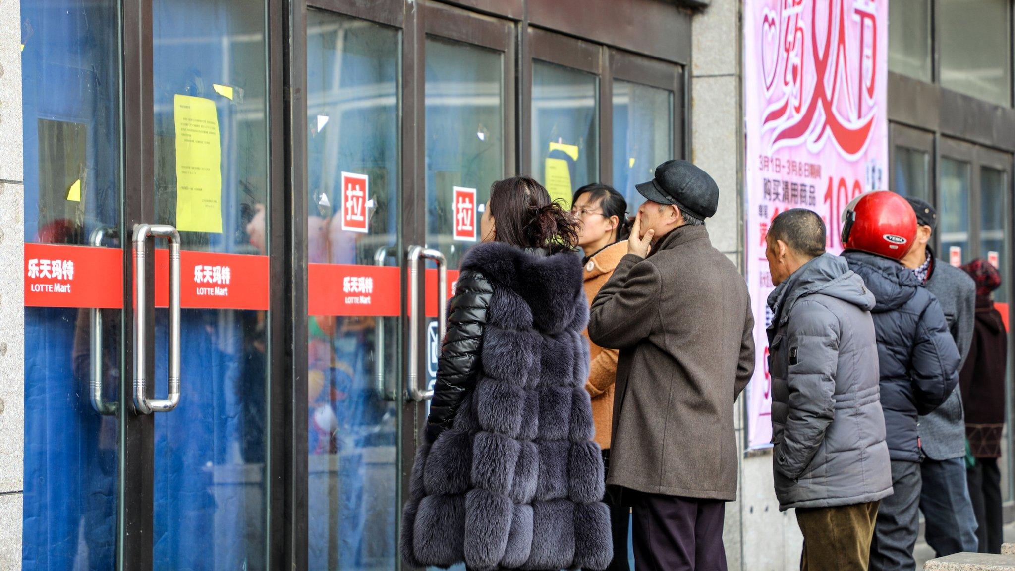 People look into a closed Lotte Mart in Dandong, Liaoning province, China, 5 March 2017