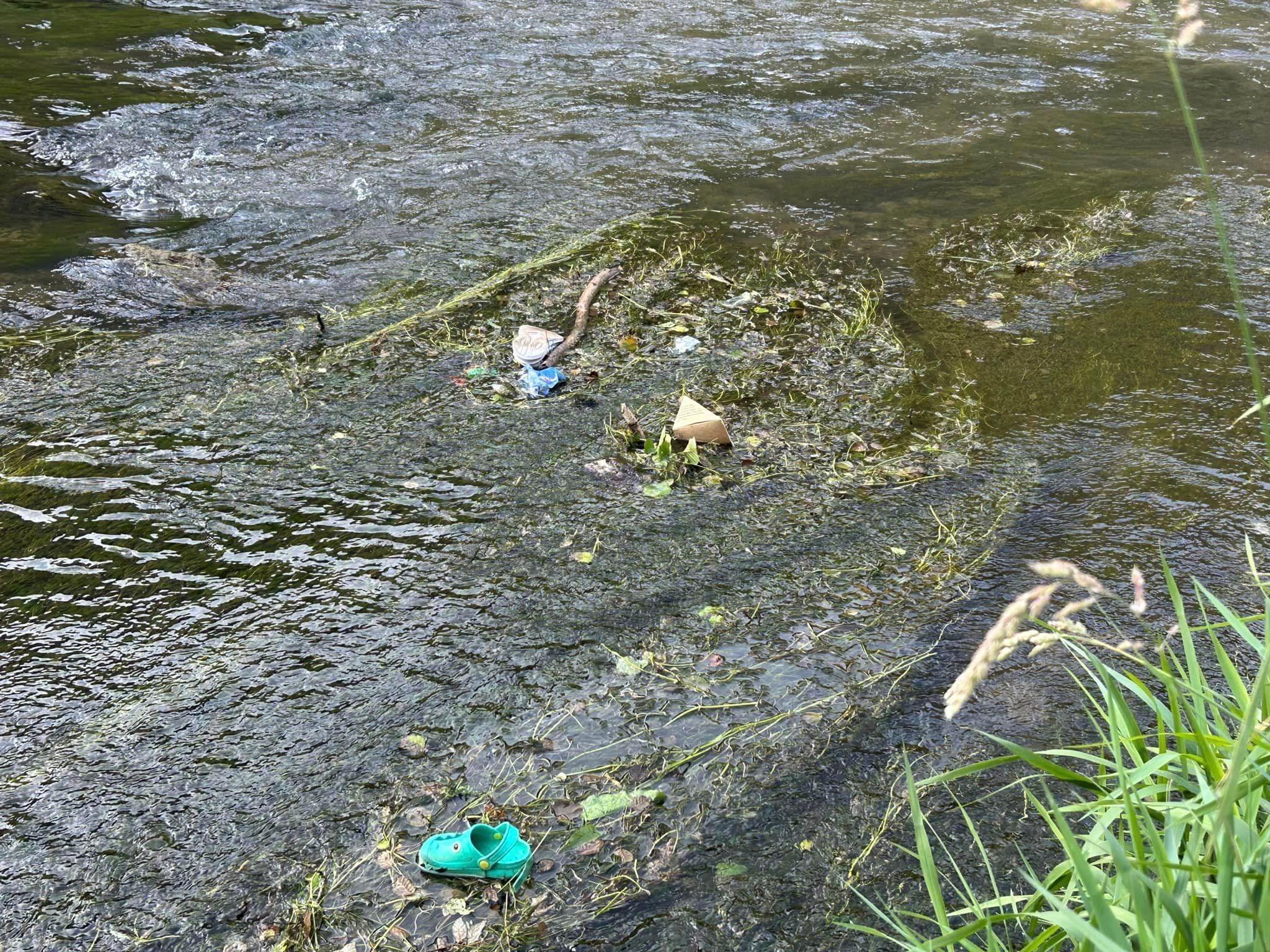 A green shoe and rubbish floating in the river