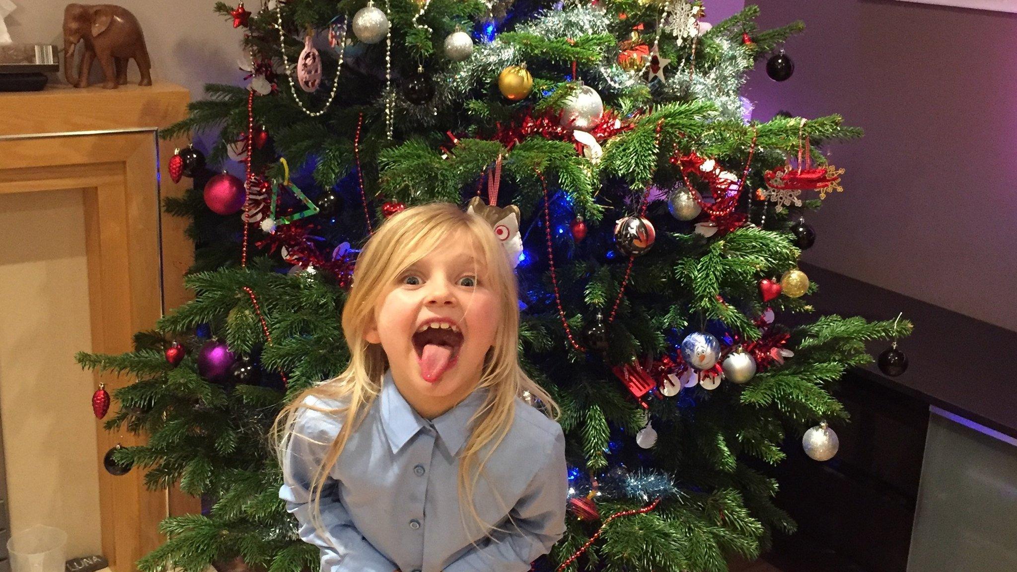 A girl in front of a Christmas tree