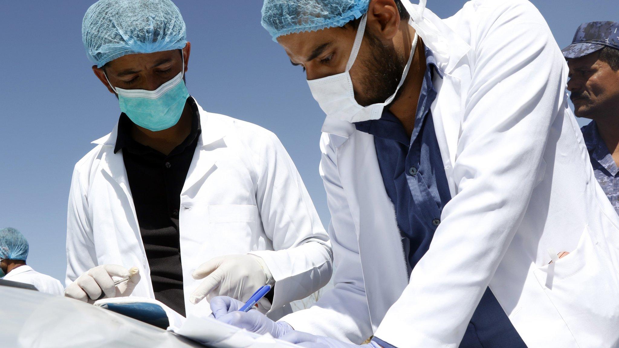 Medical staff take notes as they check people's temperature on the street as a precautionary measure against the spread of coronavirus in Yemen.