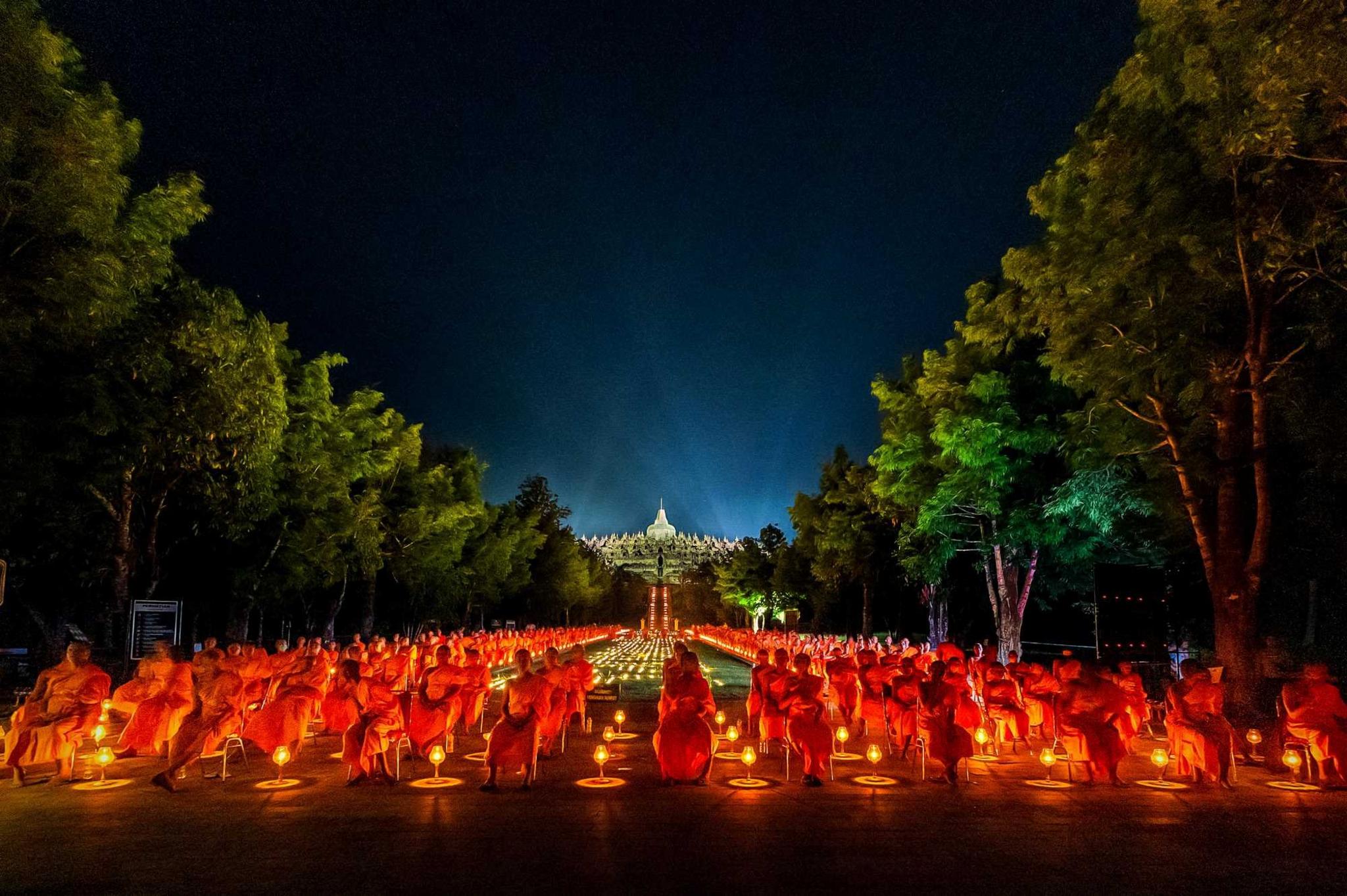 The warm light of the lanterns illuminates the hearts of pabbajja novices in the courtyard of Borobudur temple, Indonesia.