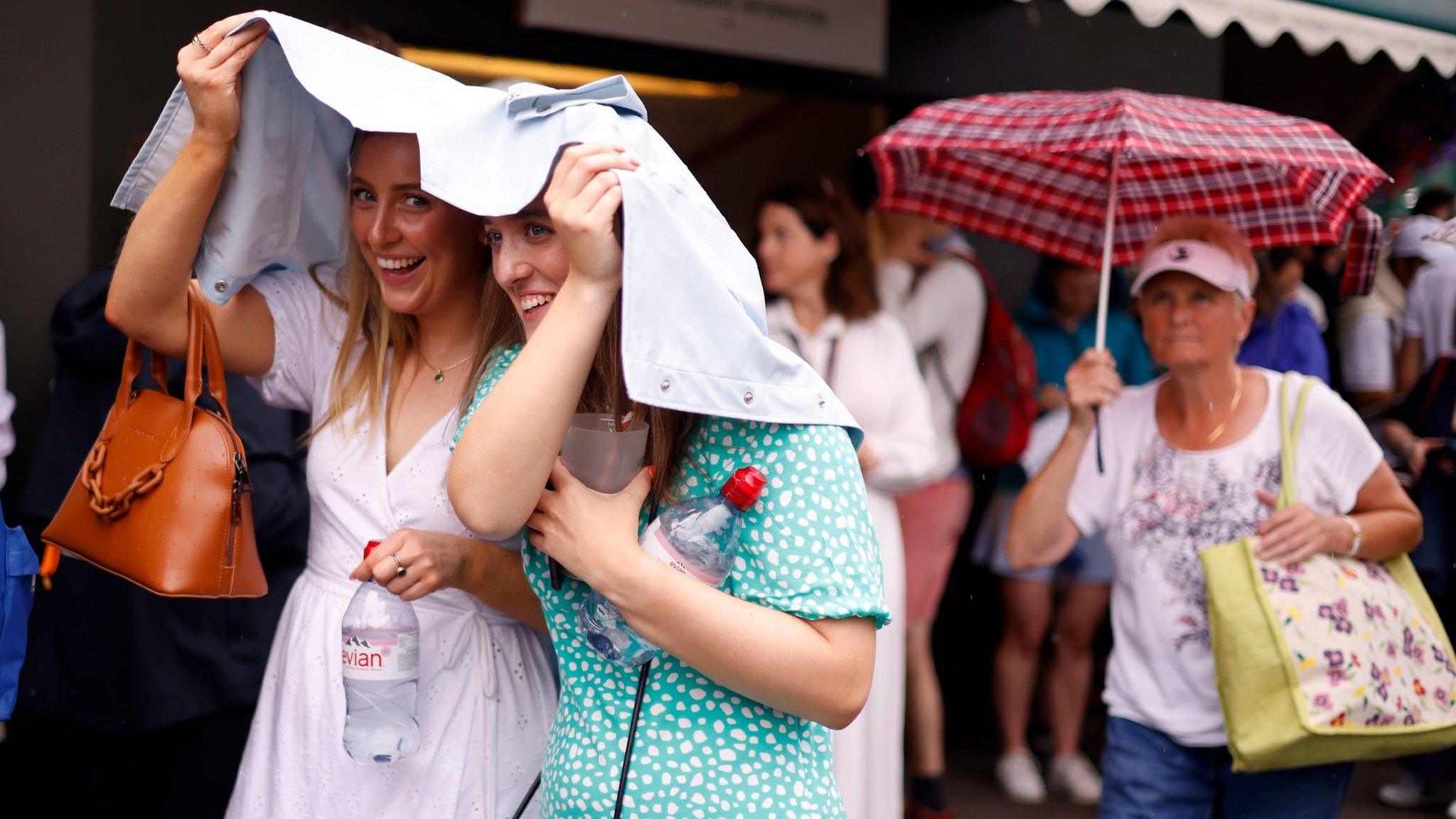 Wimbledon spectators hide from the rain under their jackets