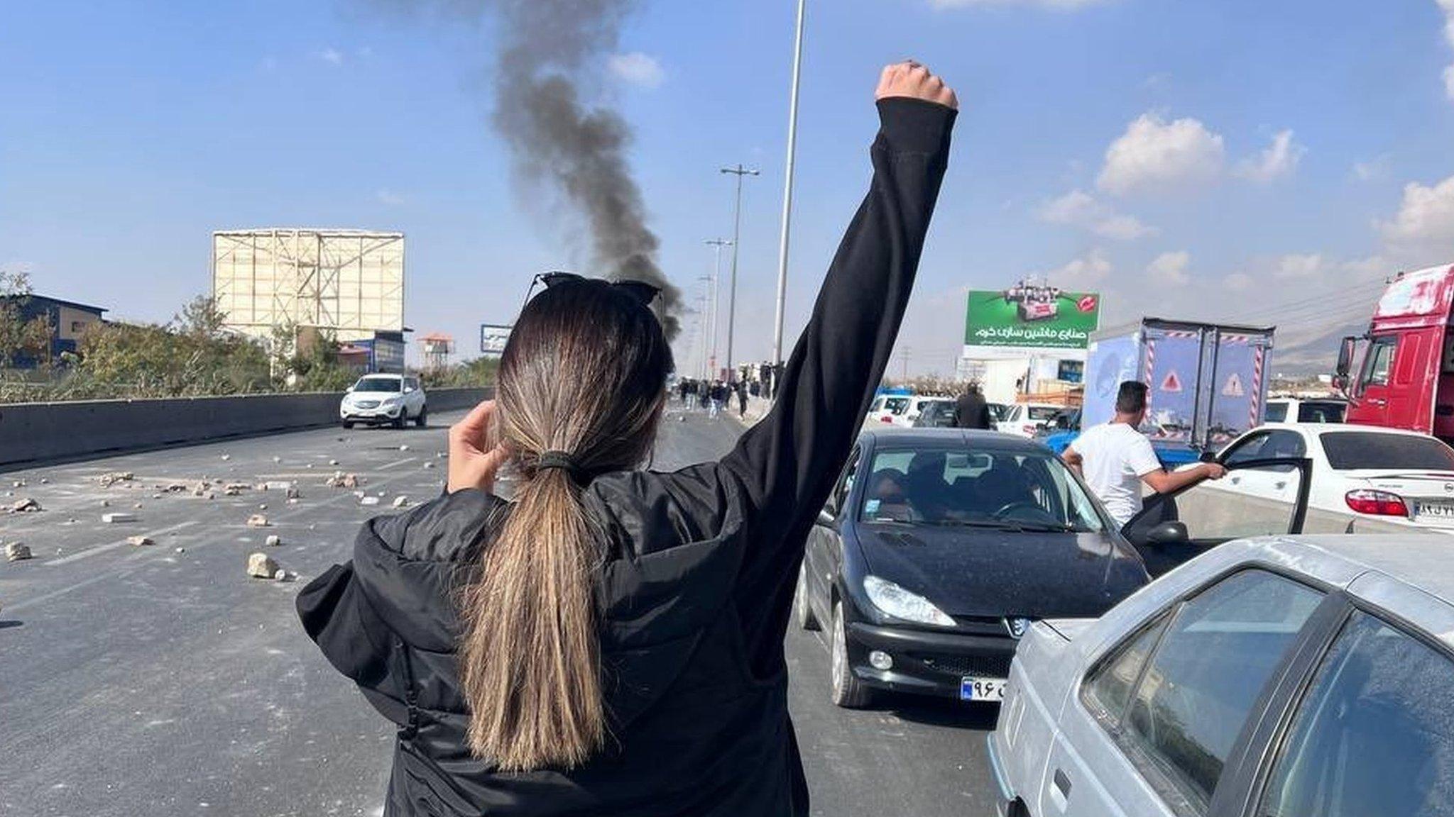 A woman without a headscarf holds up her arm during a protest in the Iranian city of Karaj on 3 November 2022