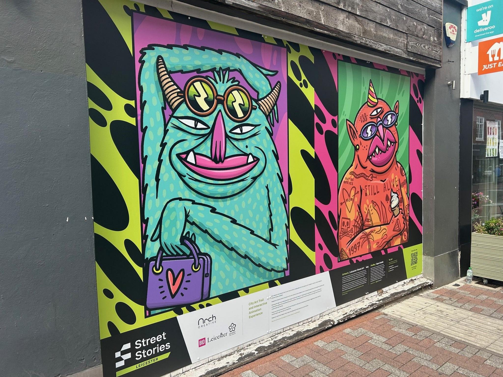 Artwork showing two cartoon creatures, one turquoise and another dark orange in colour on a shop front.