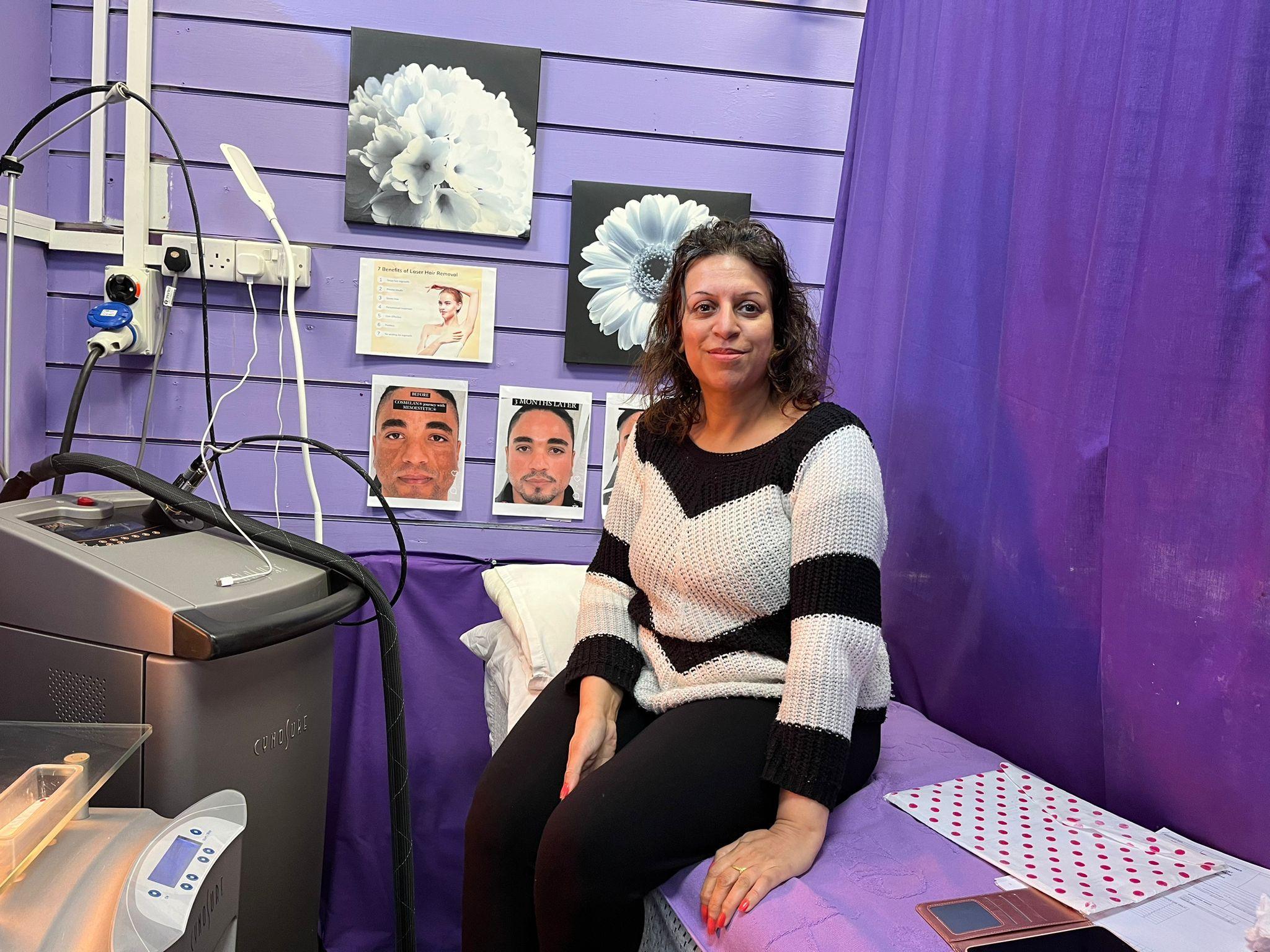 A lady sits on a bed and smiles at the camera