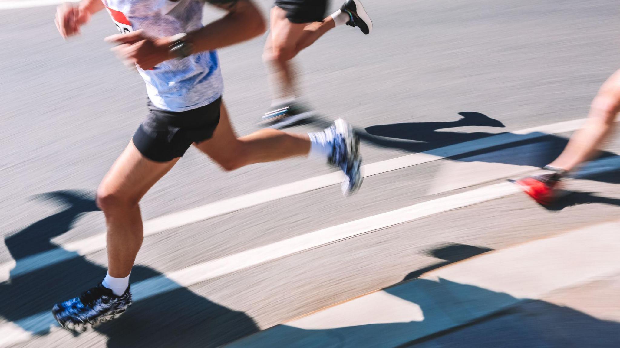 A person in exercise clothing running on a road.
